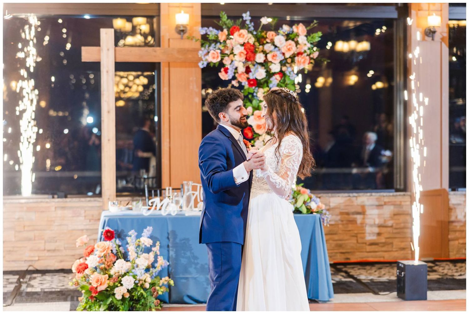 Wedding reception venue with string lights, brick walls, and colorful floral decorations.