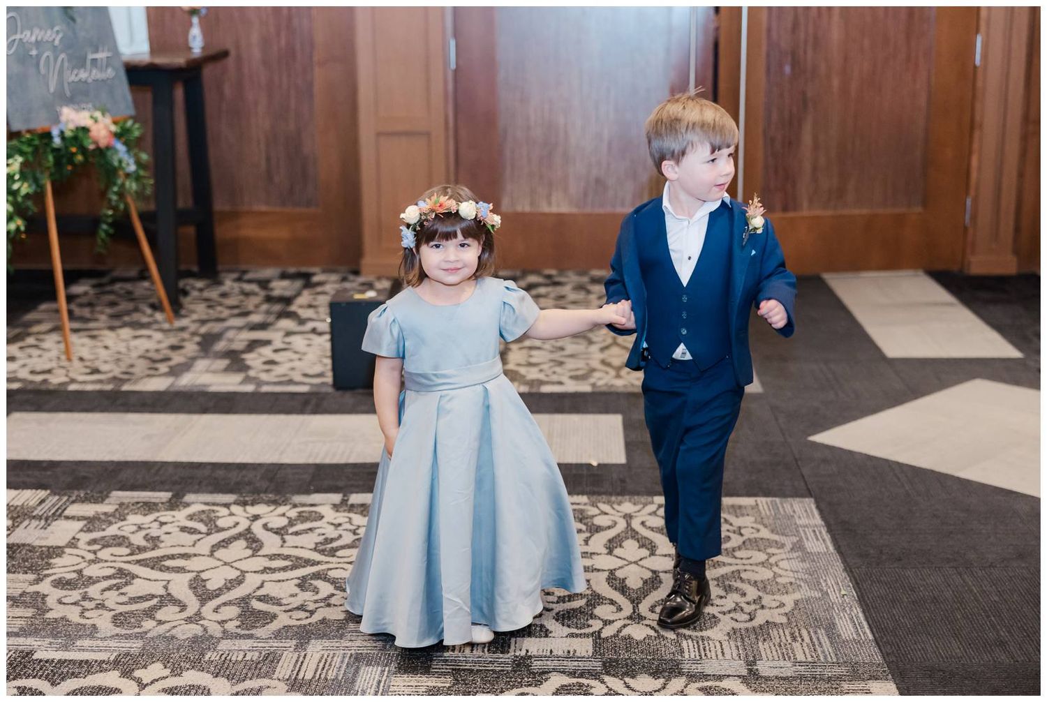 Wedding party walking down a patterned carpet in formal attire.