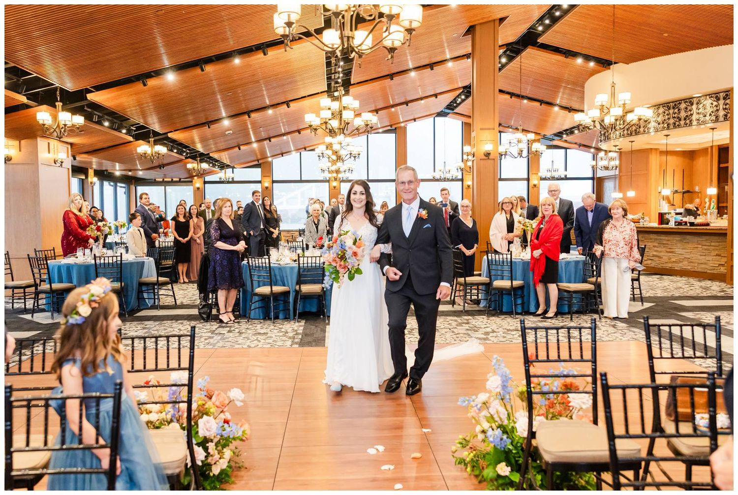 Wedding reception venue with warm wood tones, chandeliers and elegant table settings.