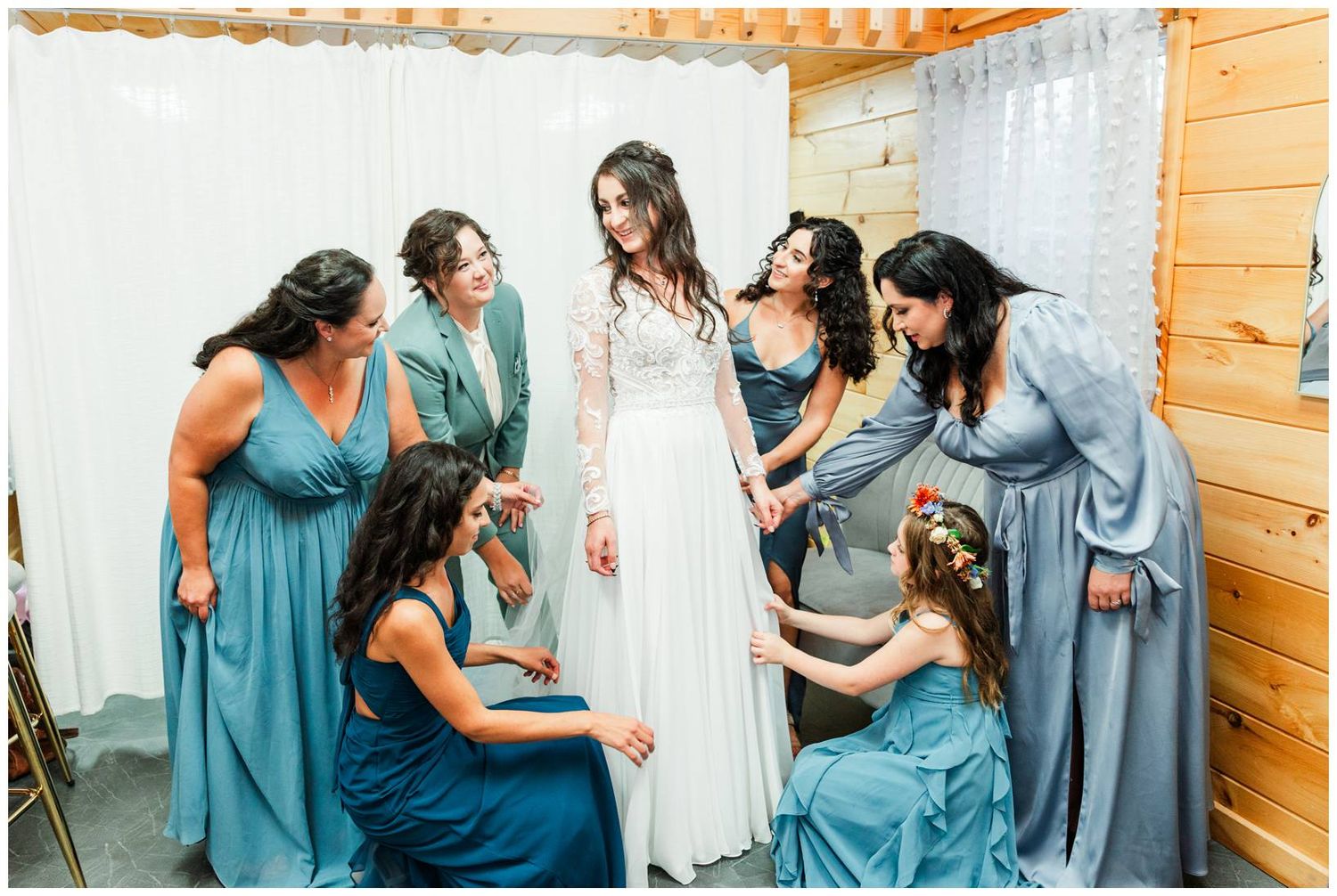 Wedding party members in teal and blue dresses sharing emotional moments while getting ready.