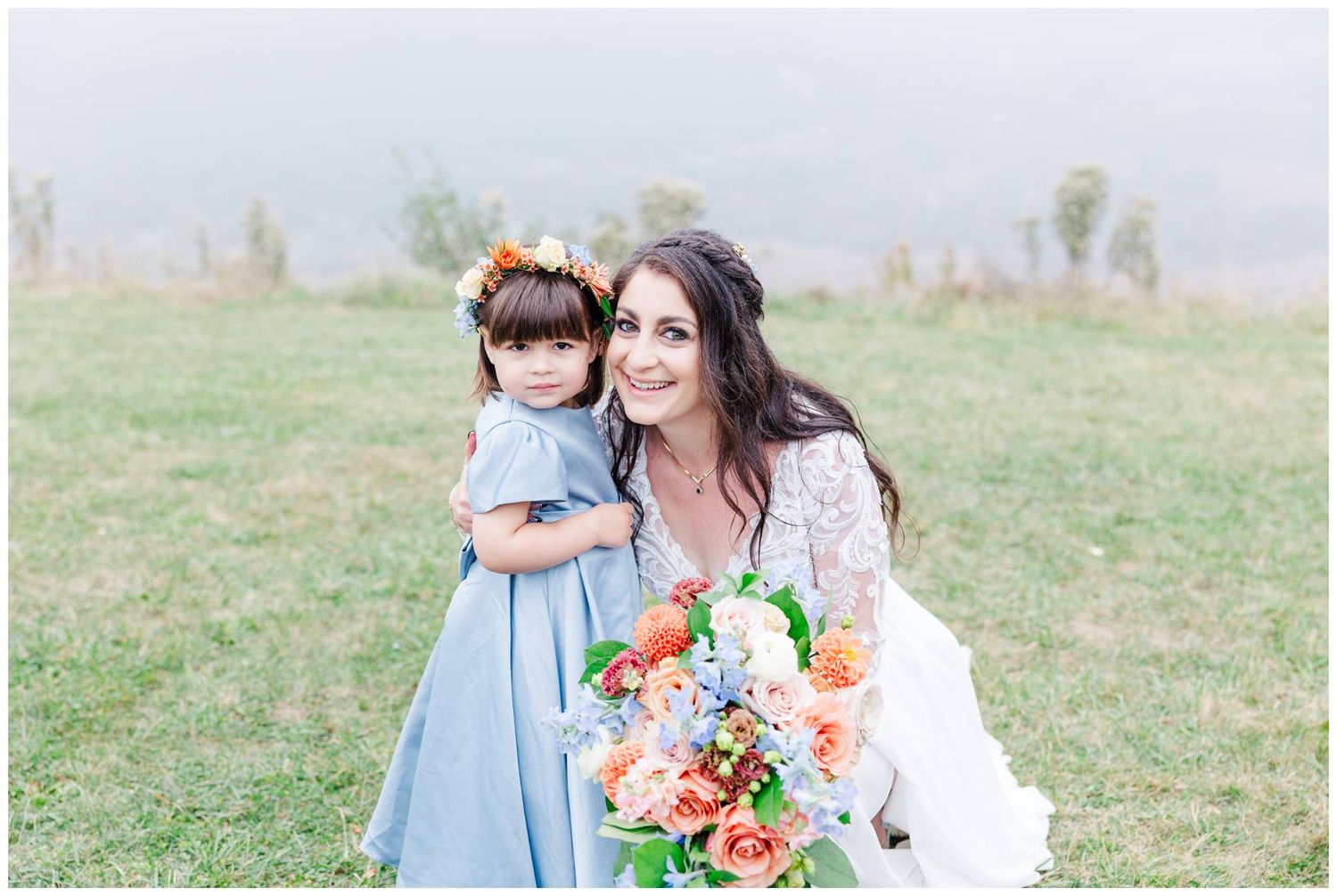 A tender outdoor portrait in a grassy field with a light blue dress and vibrant floral bouquet.