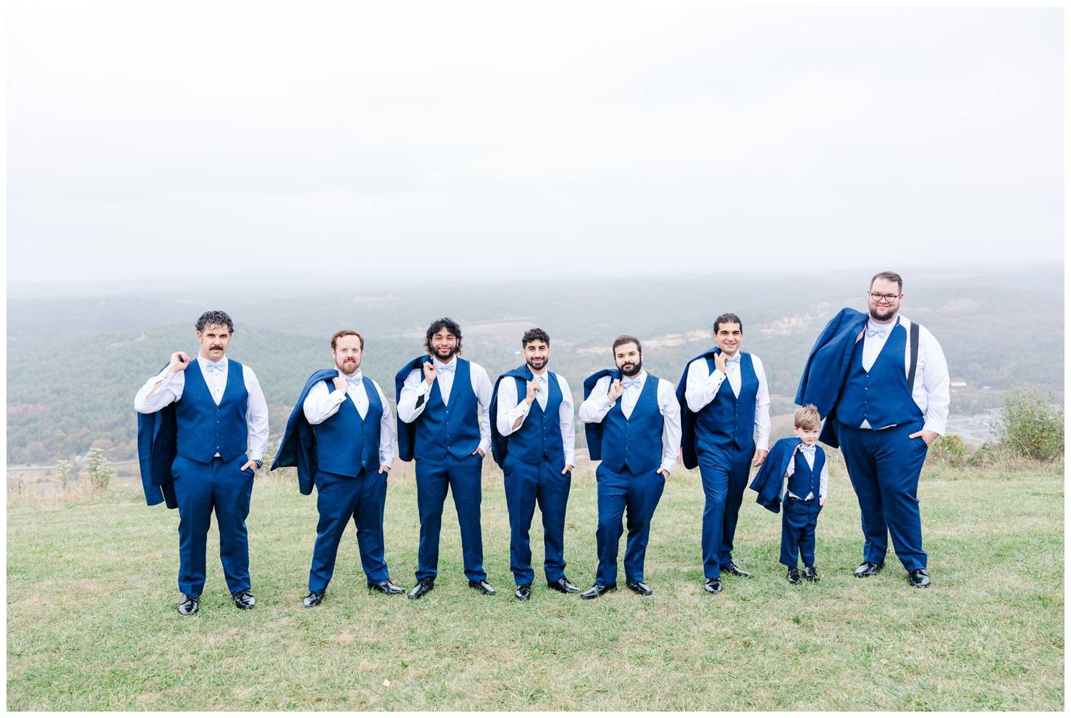 Wedding party in navy blue suits pose together on a grassy hillside in a creative progression sequence.