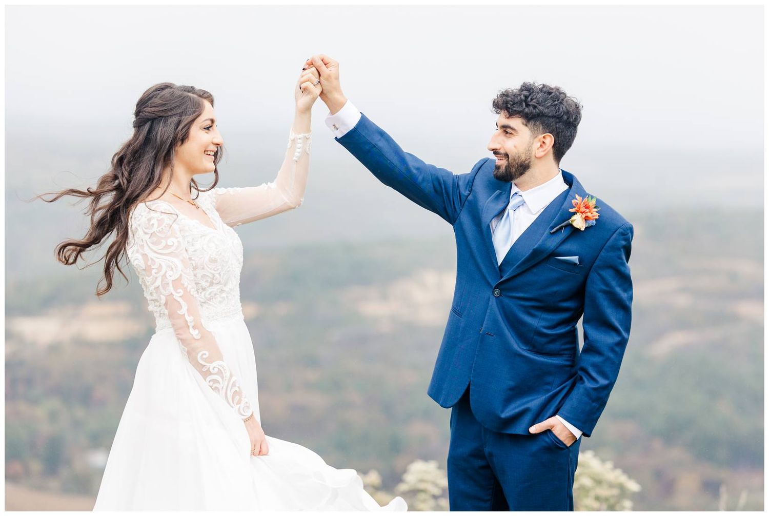 Couple dances and twirls on scenic mountain overlook during wedding photo session.