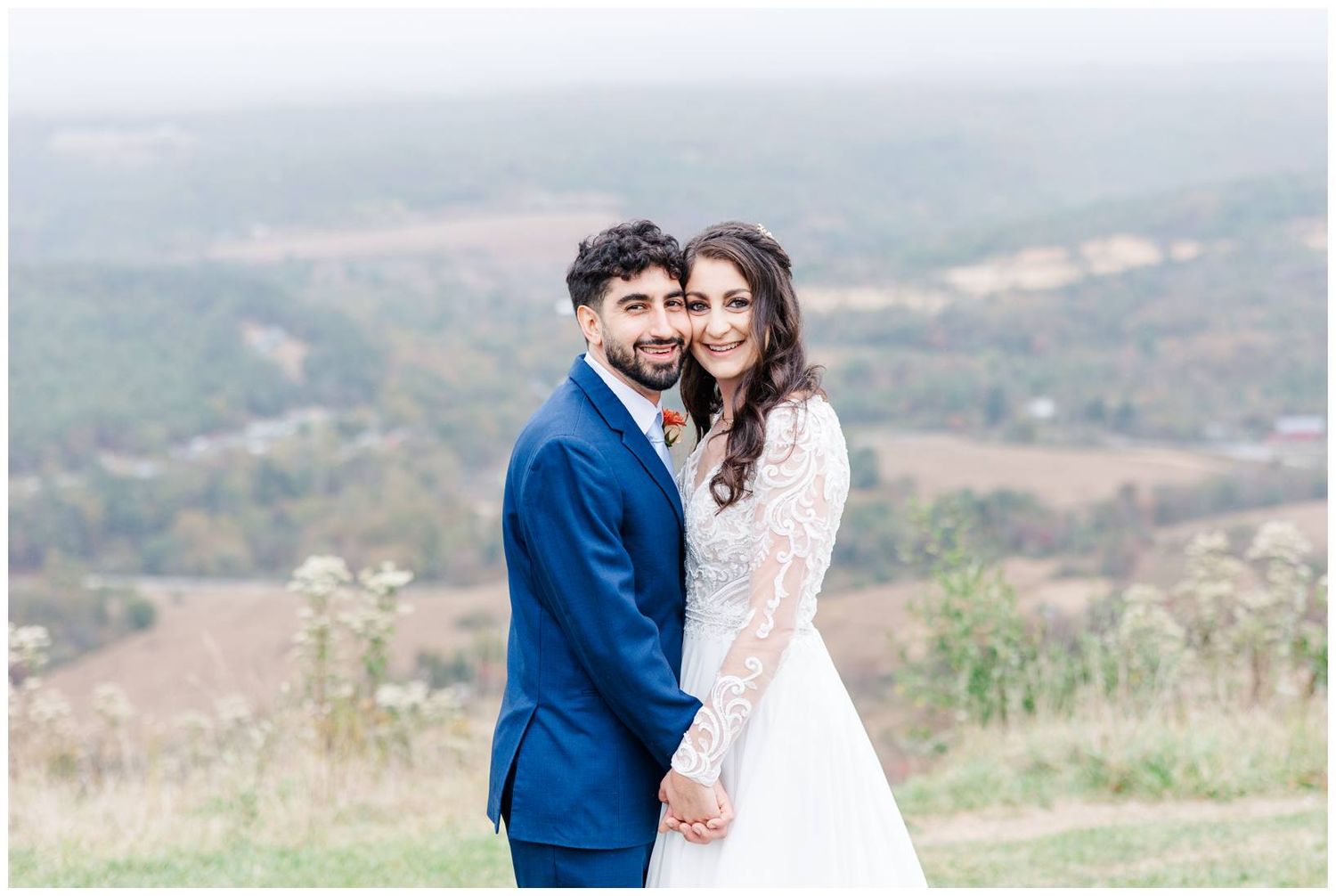 Elegant wedding couple poses in a scenic mountain meadow setting.