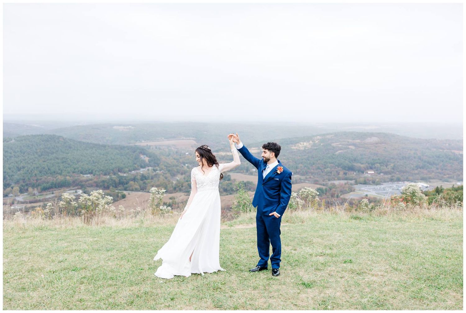 Wedding party gathered on a hilltop meadow with sweeping mountain views.