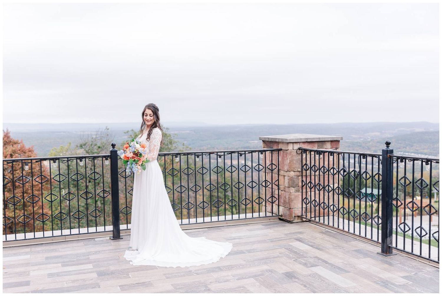 Elegant wedding portraits on stone terrace with sweeping mountain views and iron railings.