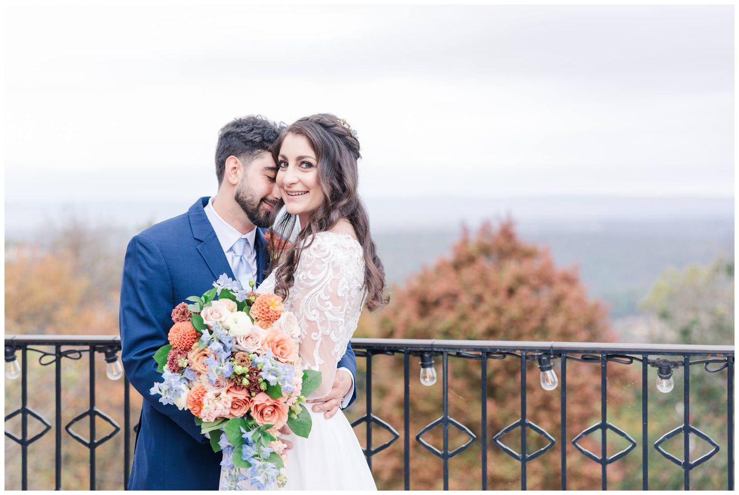 Romantic wedding portrait at a scenic overlook with mountains and autumn colors in the distance.