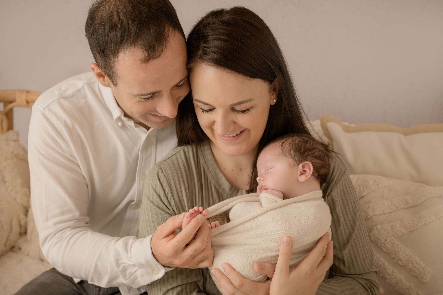 A tender family moment captured in a series of photos showing parents bonding with their baby on a cozy bed.