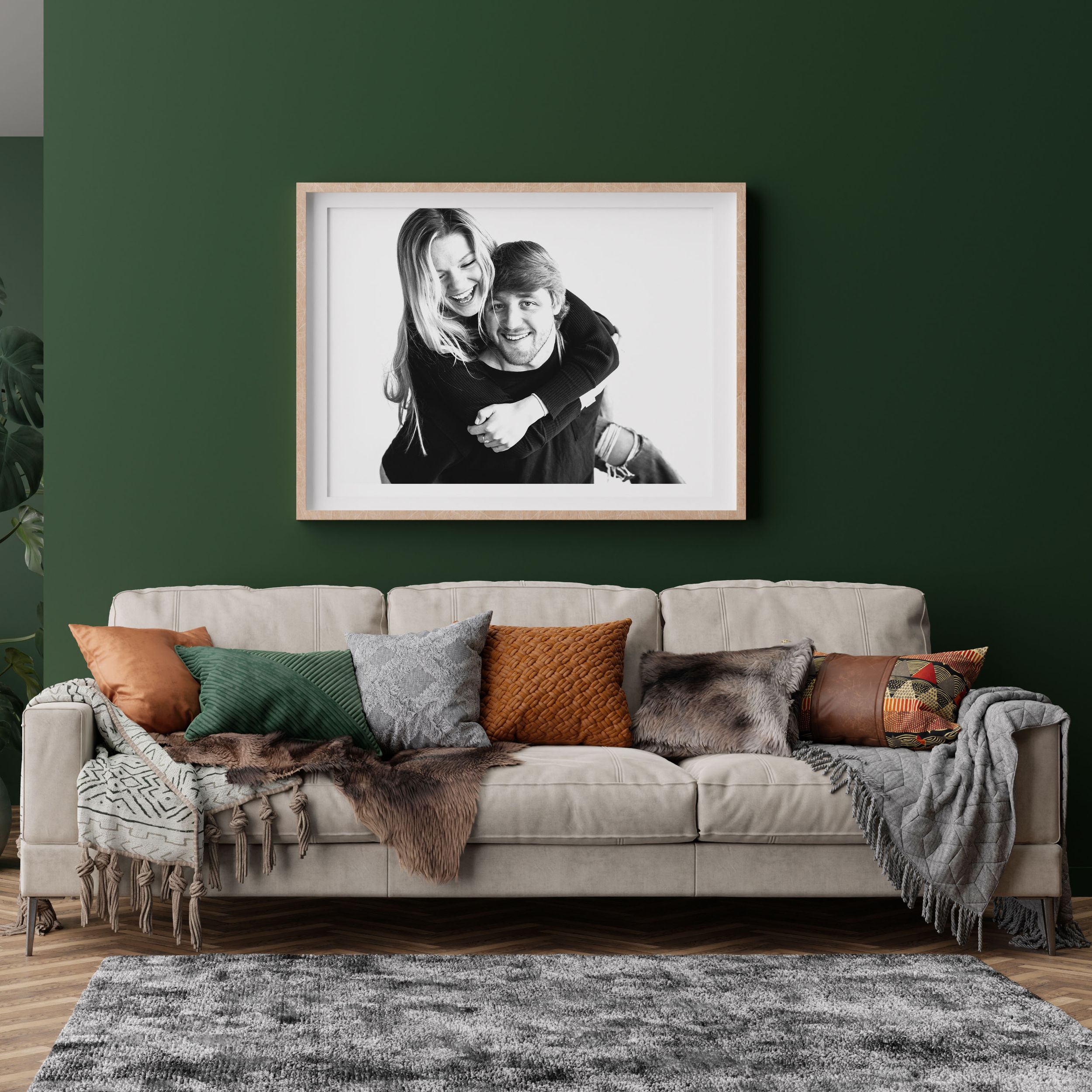 Modern living room with dark green walls, grey sectional sofa, and black and white artwork displayed above.