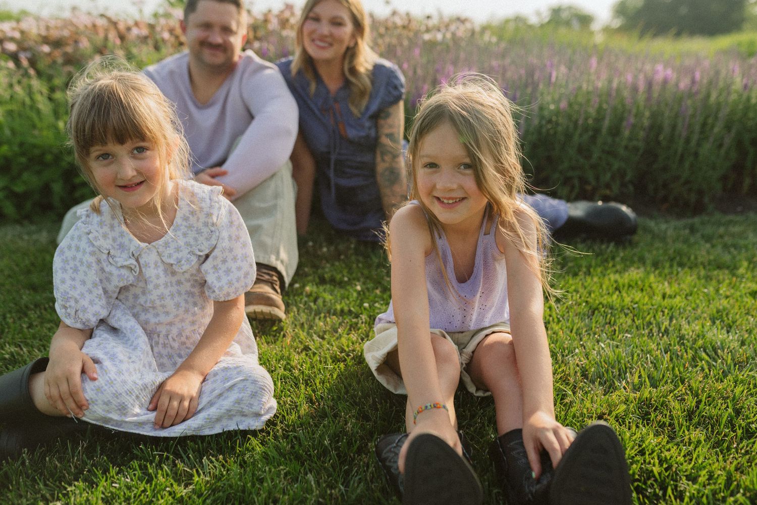 People lounging casually on grass near blooming flowers in a garden setting.