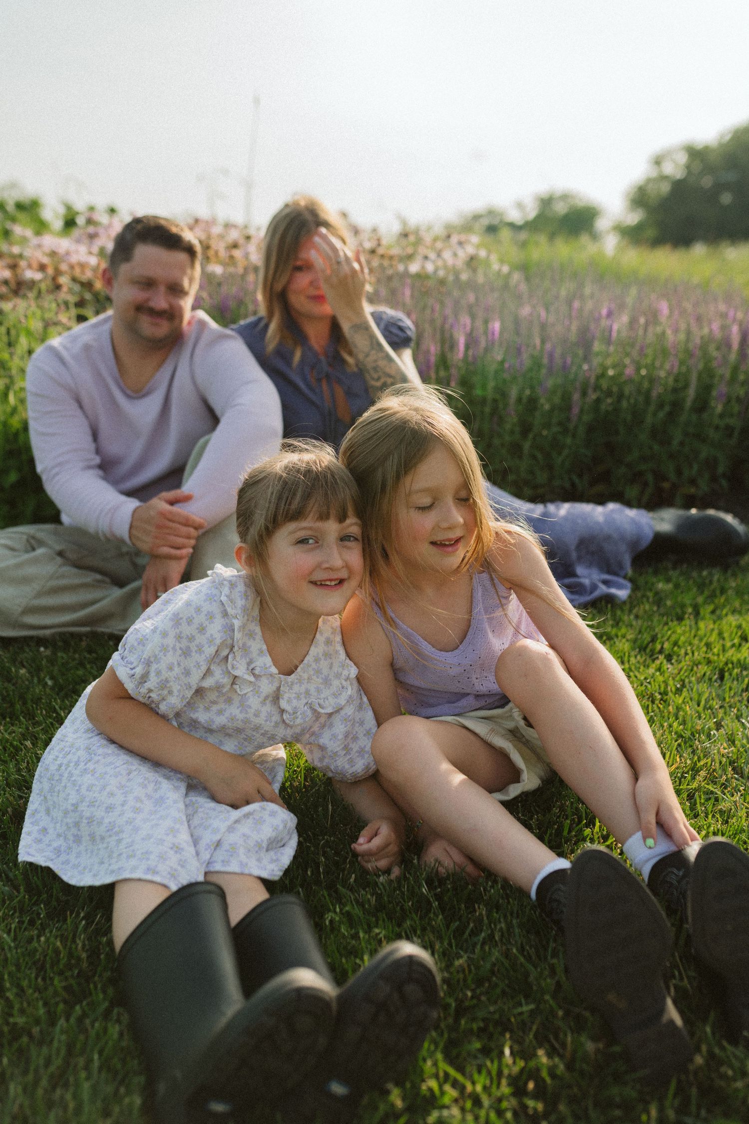 A cheerful group enjoys quality time outdoors among purple wildflowers on a grassy field.