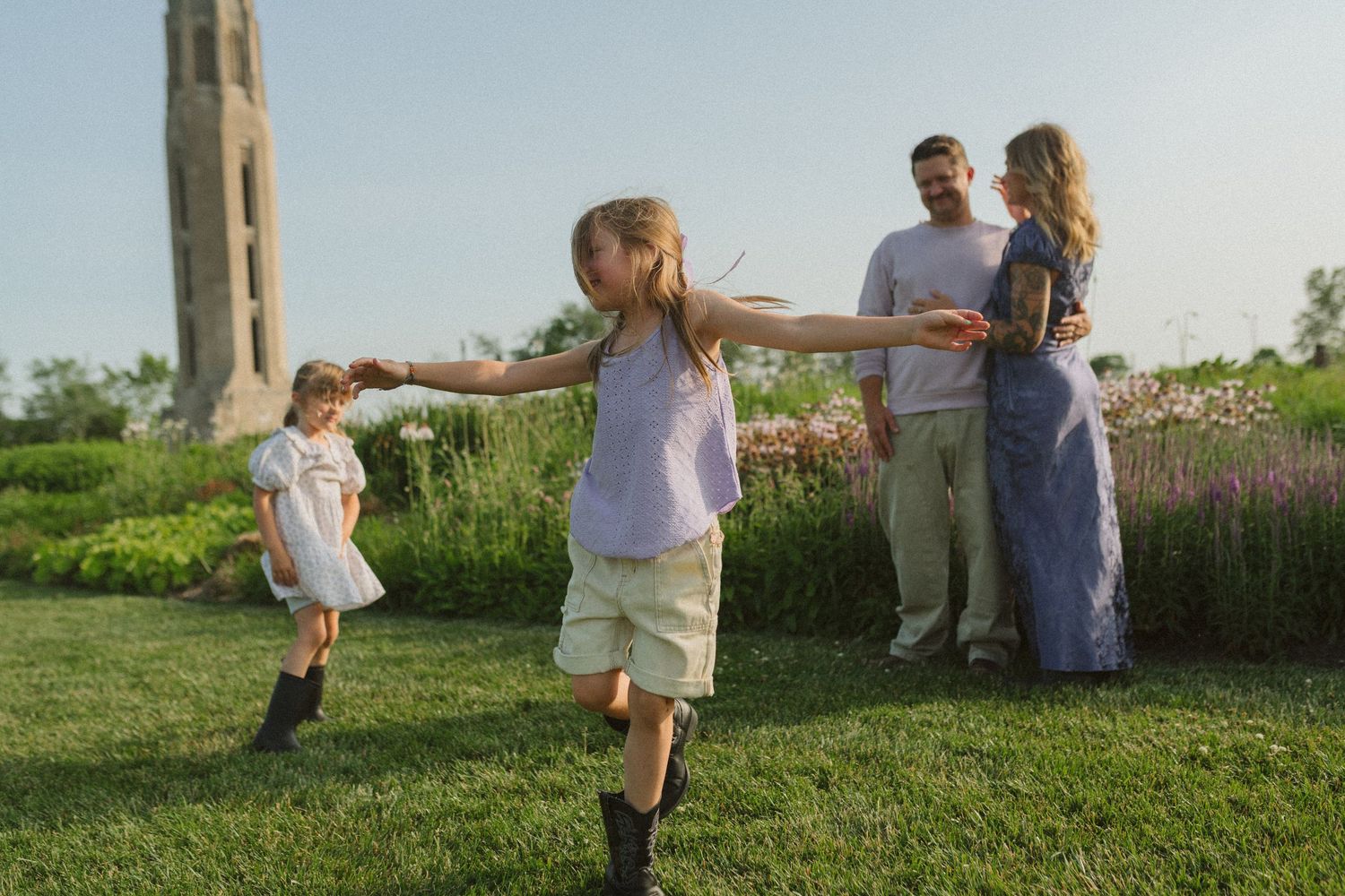 Children playing and running together on a grassy field during a summer evening.