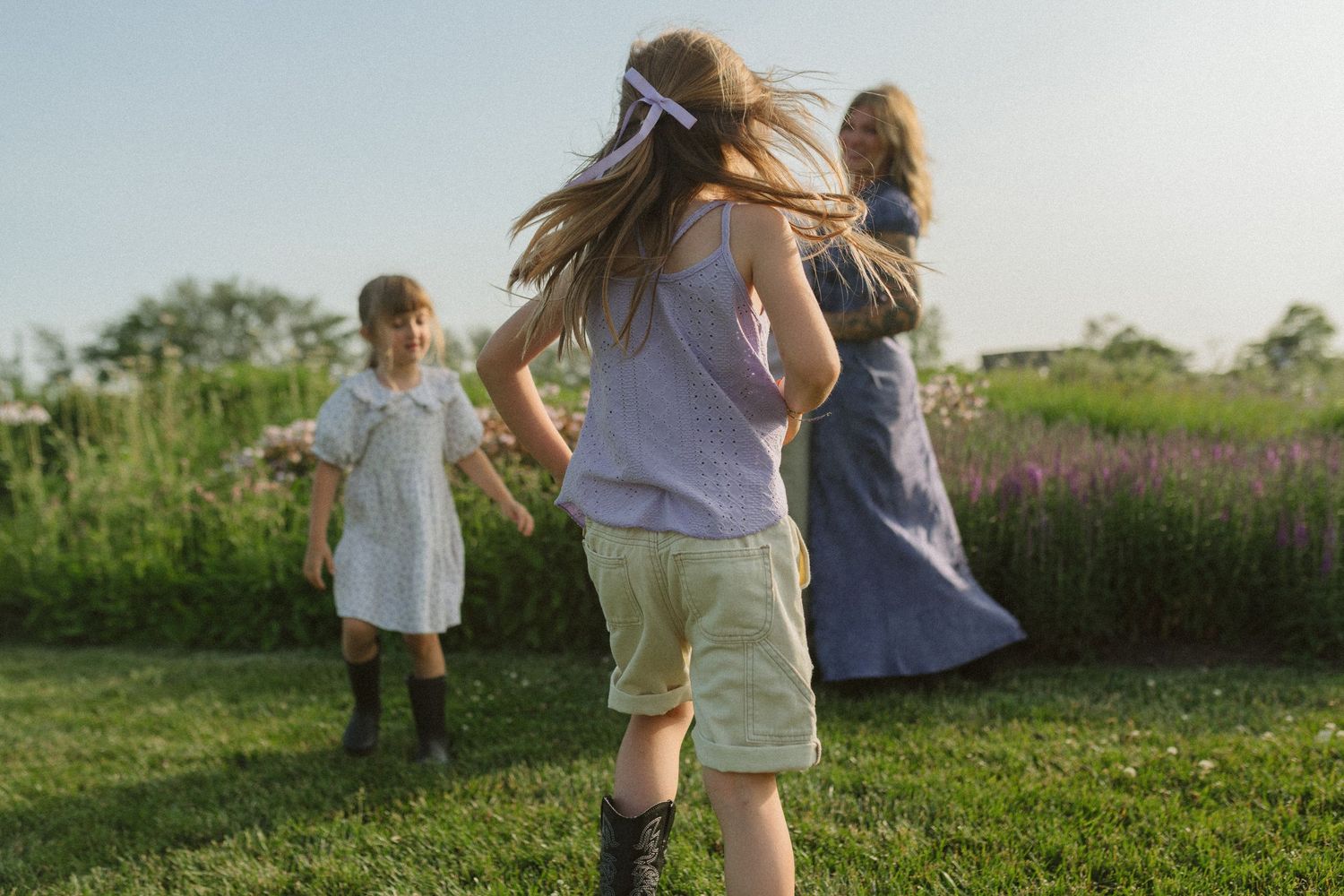 A joyful scene of people dancing and playing together in a grassy field during golden hour.