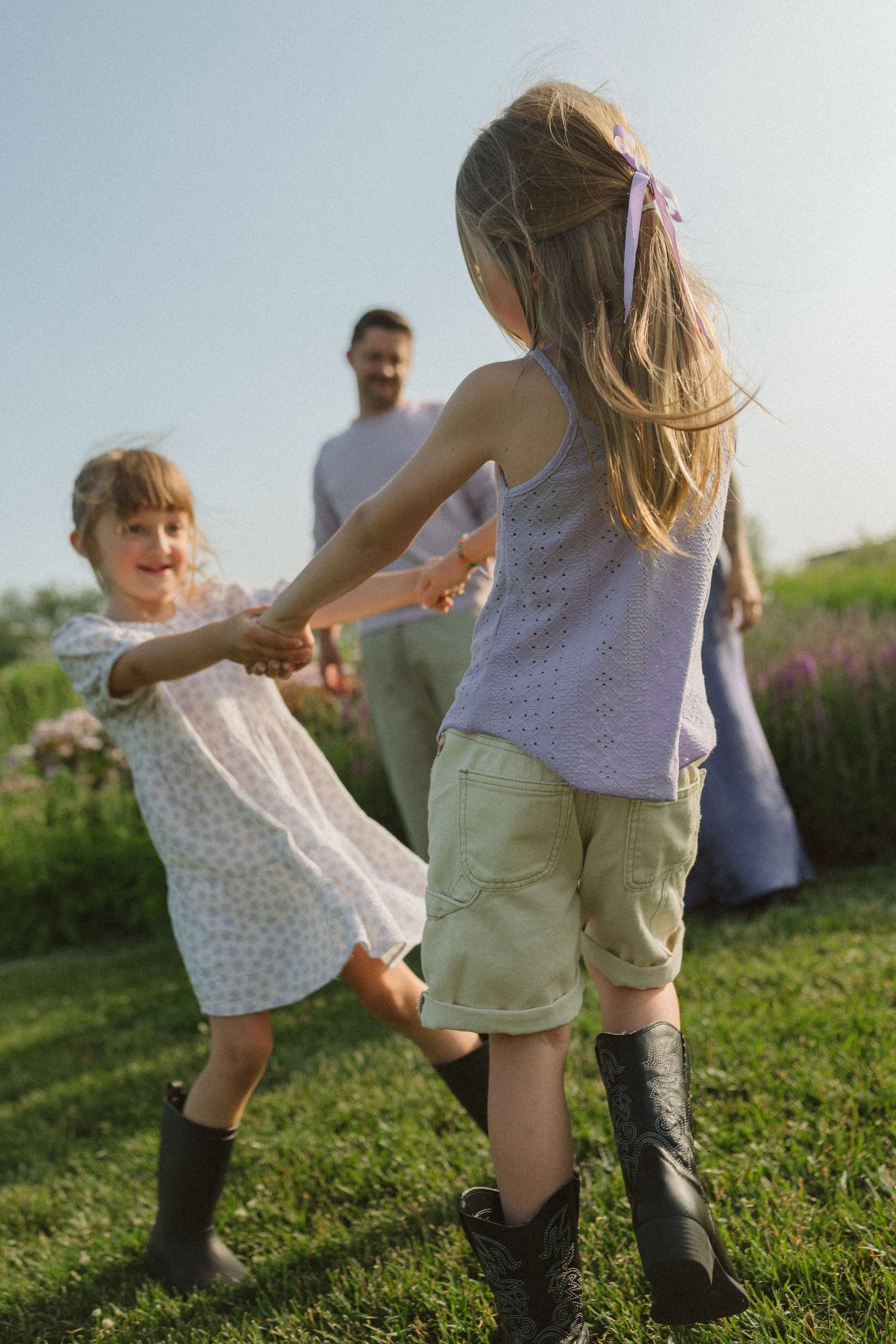 A playful sequence of people dancing and spinning in a grassy field during golden hour.