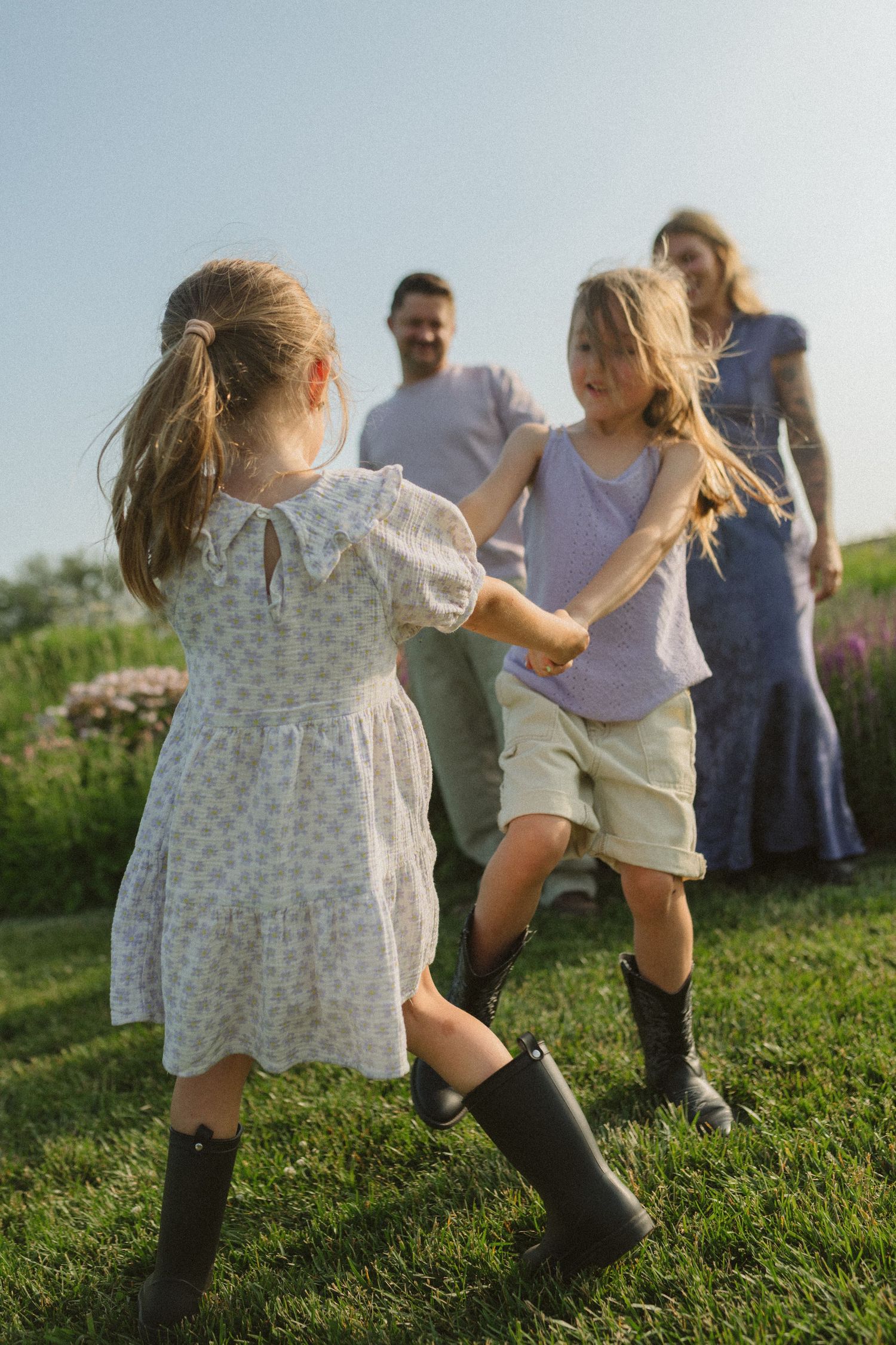 Children play and run together on a grassy hillside during a sunny afternoon.