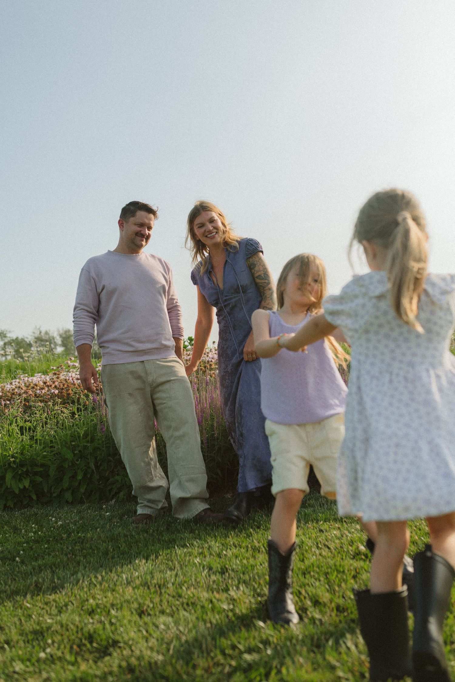 People enjoying a playful moment together on a hillside during a warm summer evening.