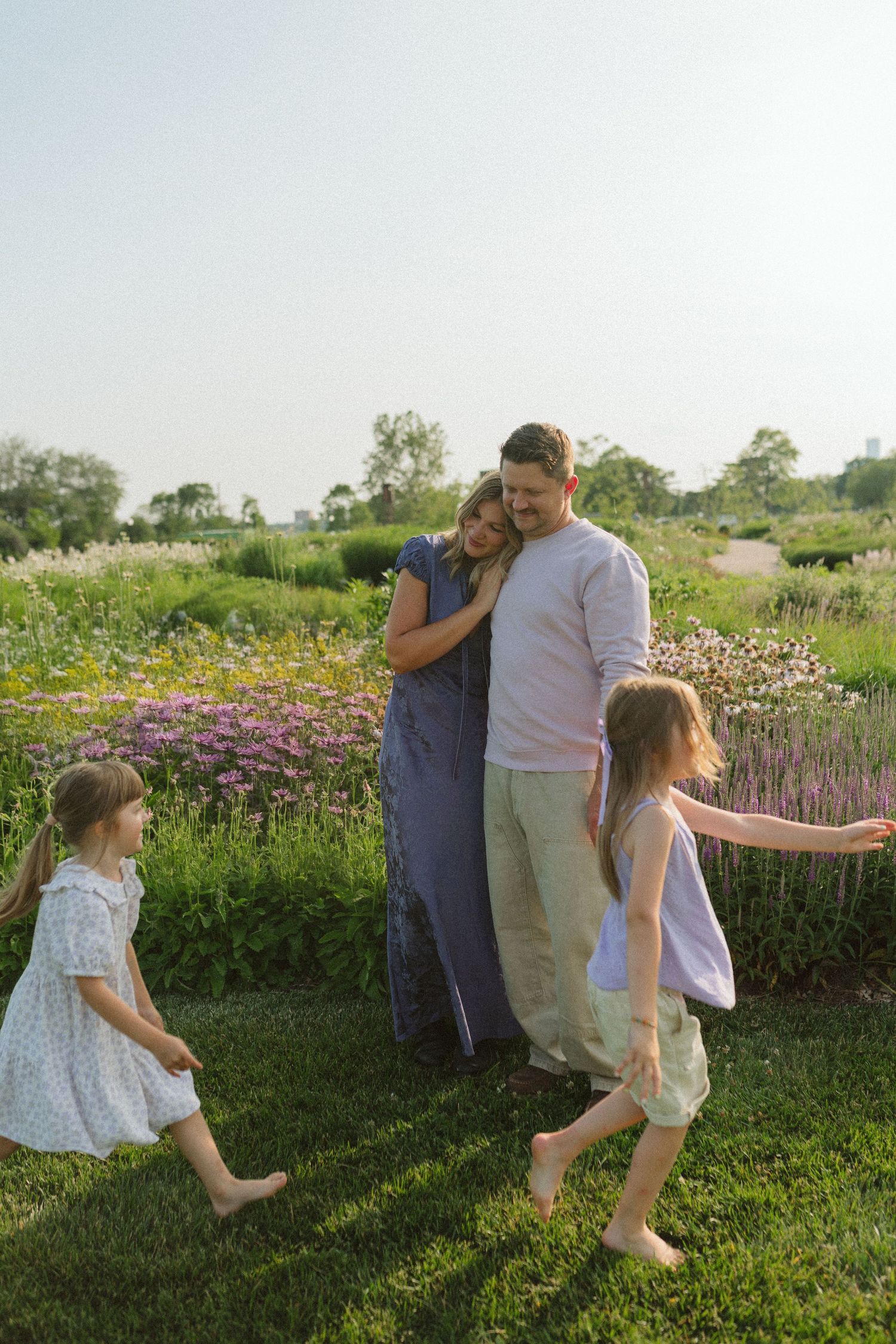 Family enjoying a candid moment together in a blooming flower garden on a sunny summer day.