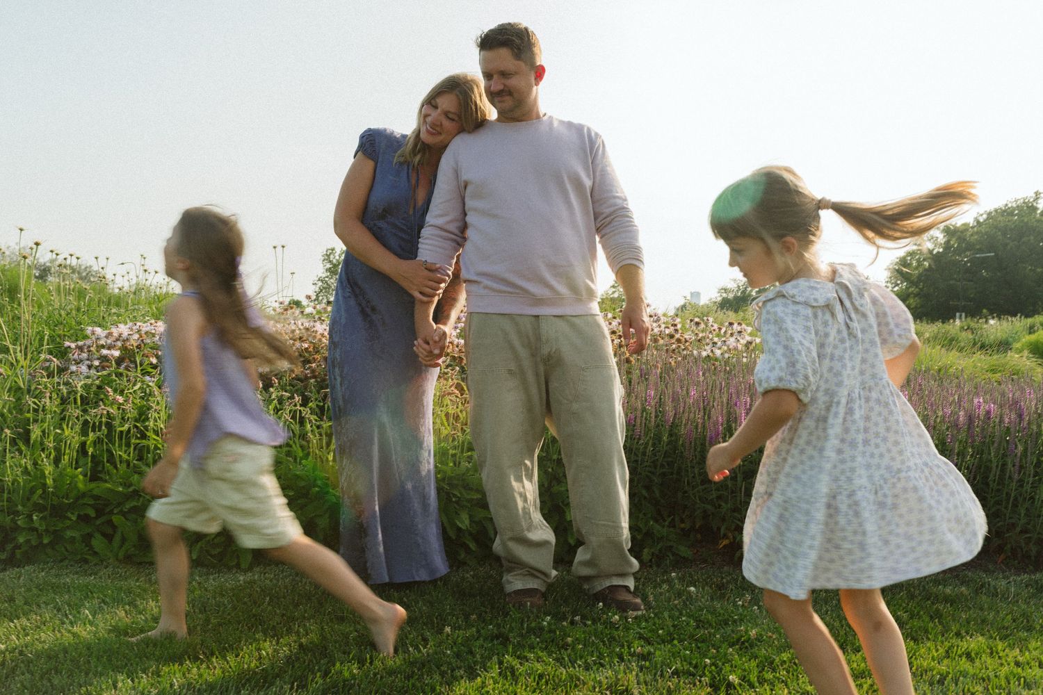 People enjoying outdoor activities in a flower-filled meadow on a sunny day.