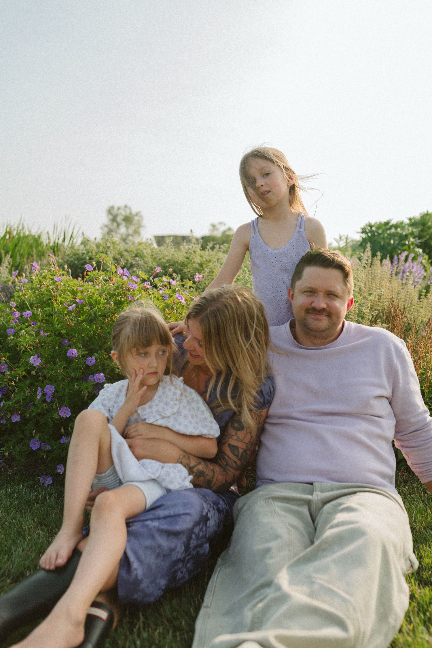 A tender family moment shared while relaxing in a flowering meadow at sunset.
