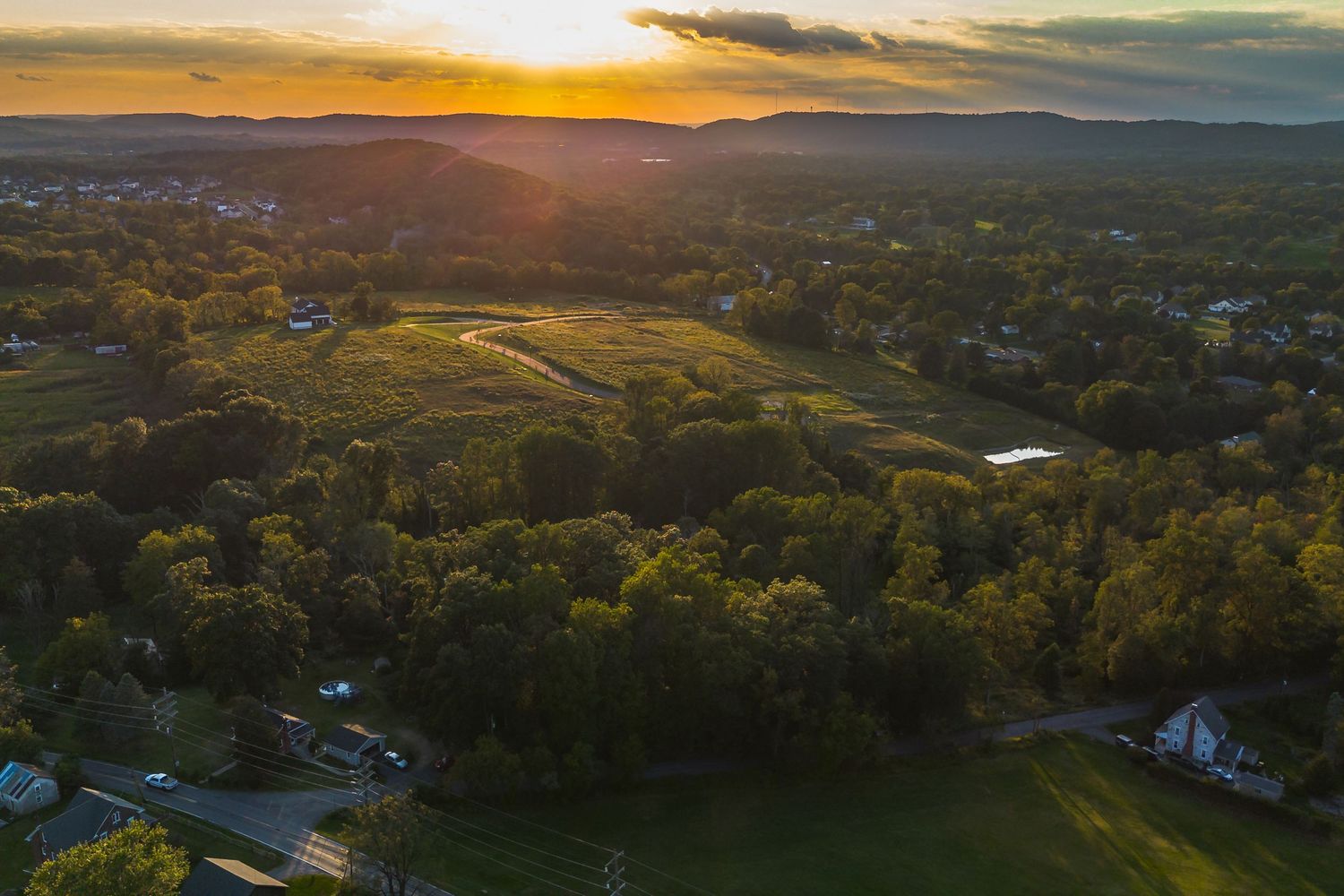 Stunning aerial sunset view over rolling hills and suburban neighborhoods.