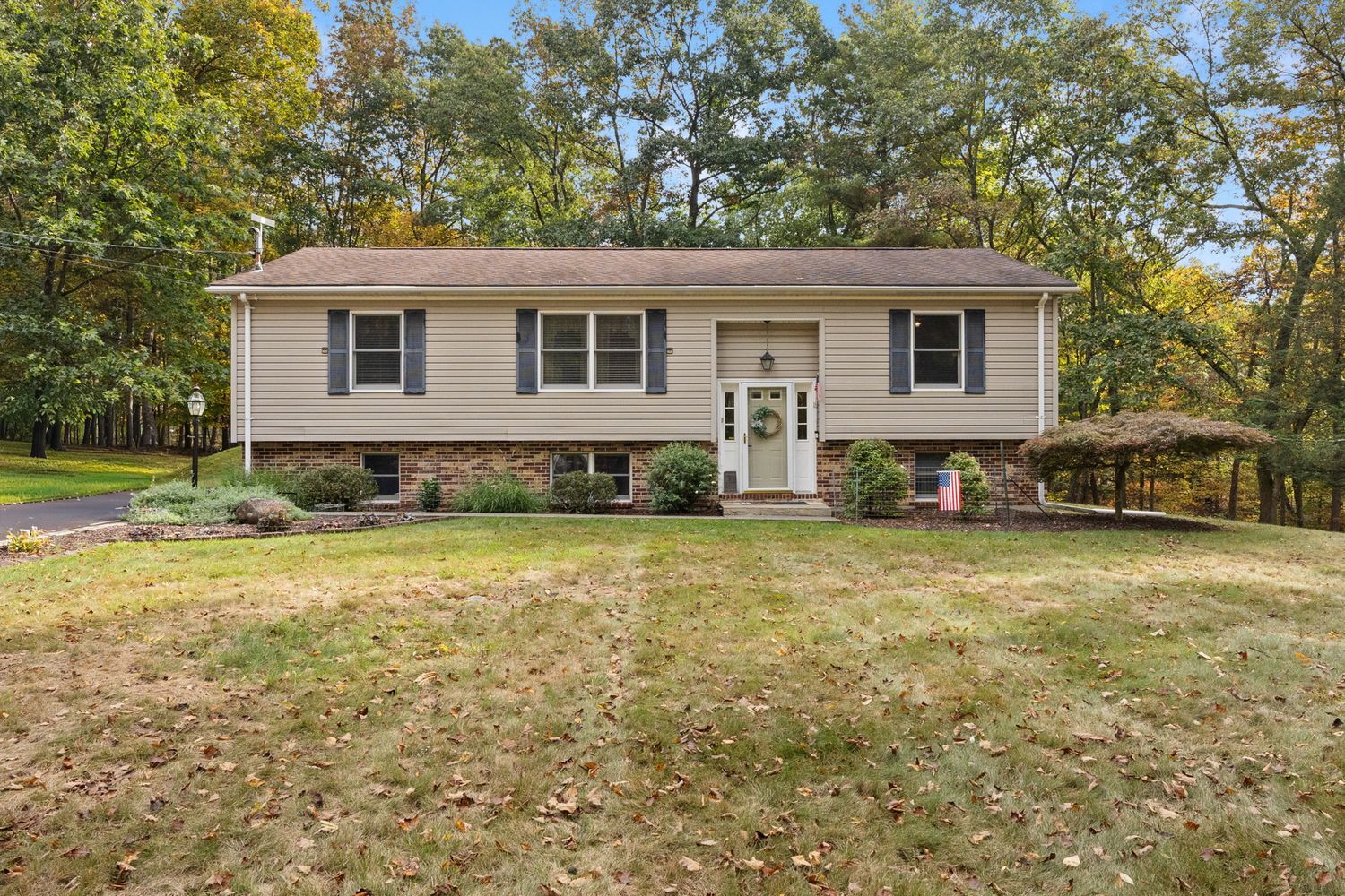 Front exterior view of a ranch-style home with landscaped yard in autumn.