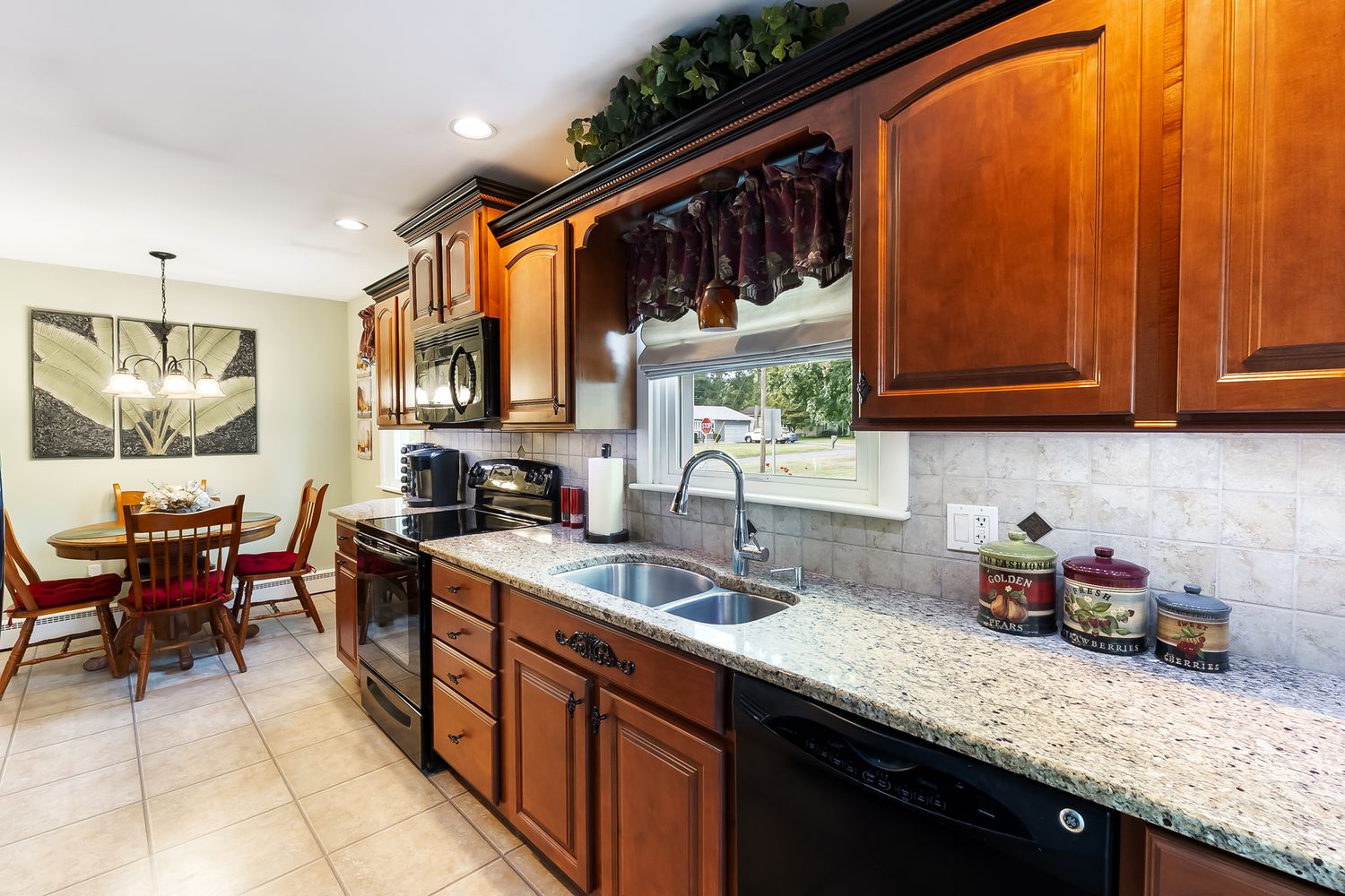 Modern kitchen interior with granite countertops, wood cabinets, and stainless steel appliances.