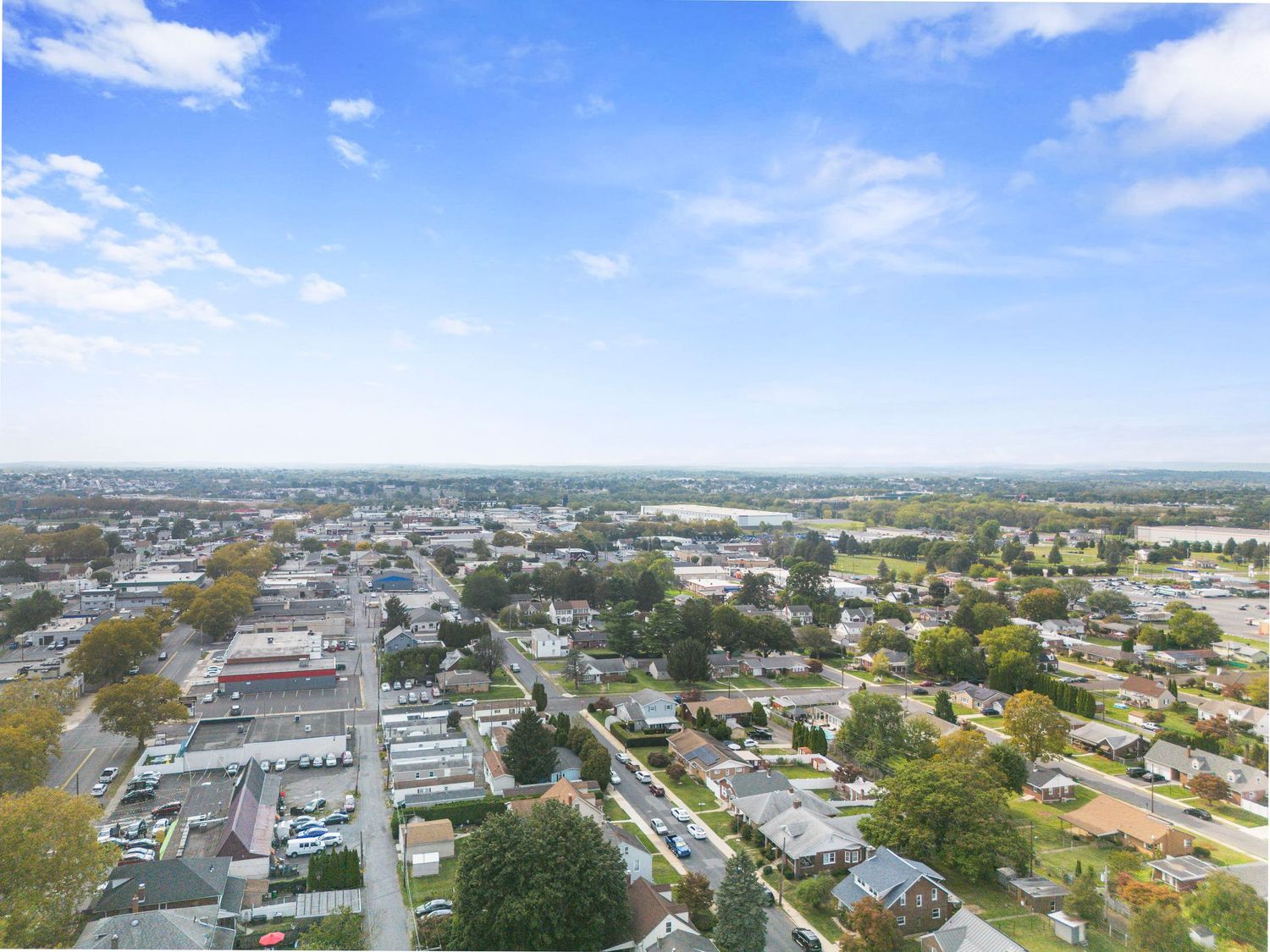 Wide aerial view of a suburban town with commercial buildings and residential areas.