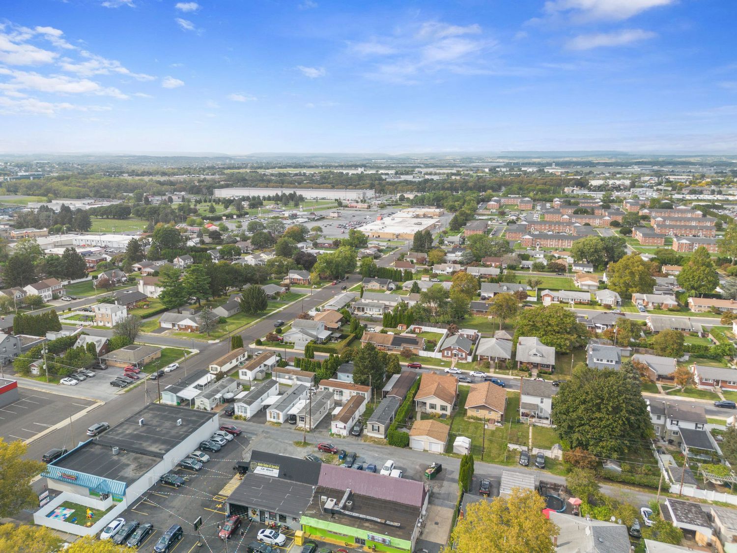 Birds-eye view of commercial and residential buildings in an urban area with green spaces.