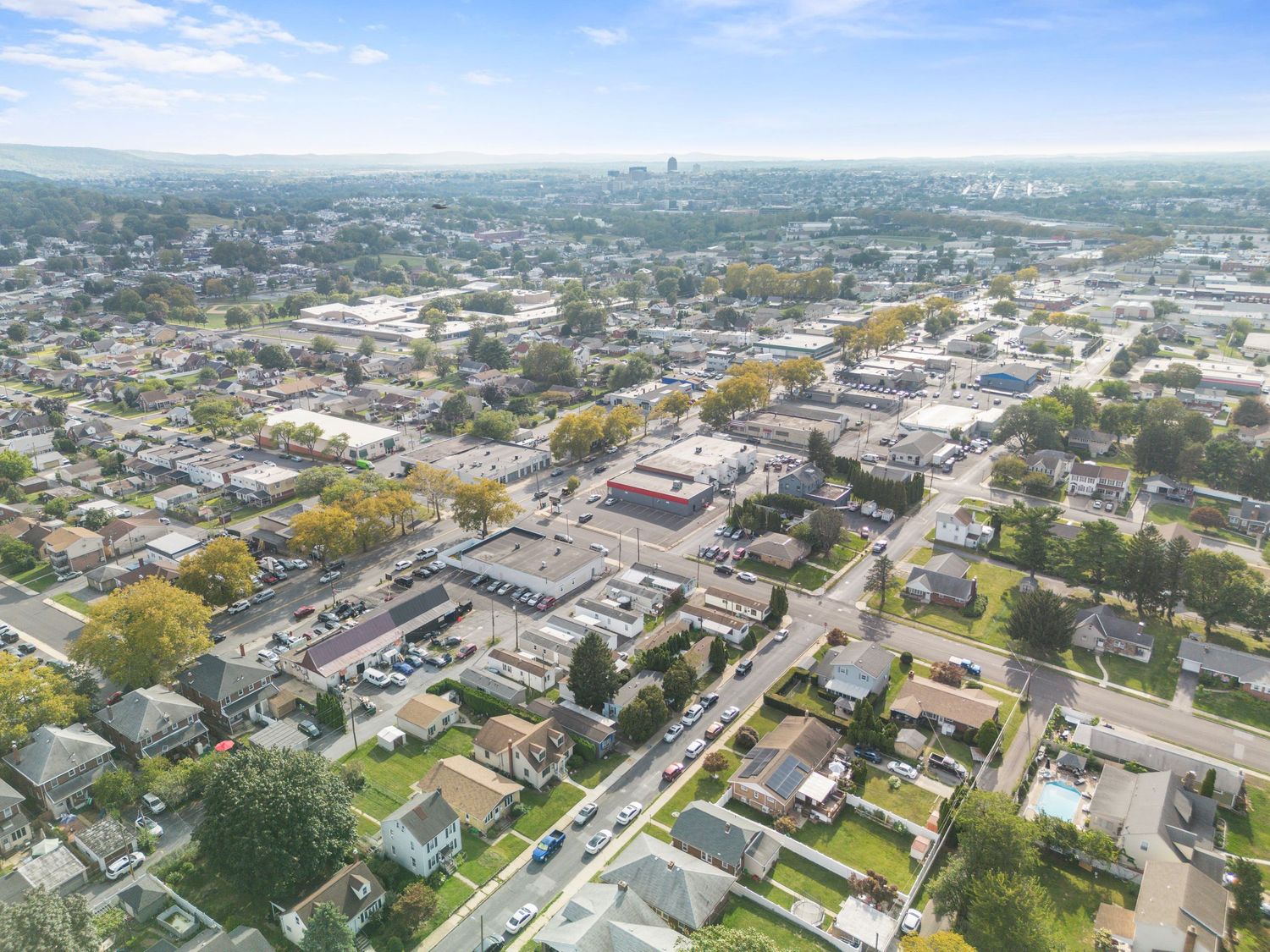 Aerial panoramic view of a suburban neighborhood with residential buildings and tree-lined streets.