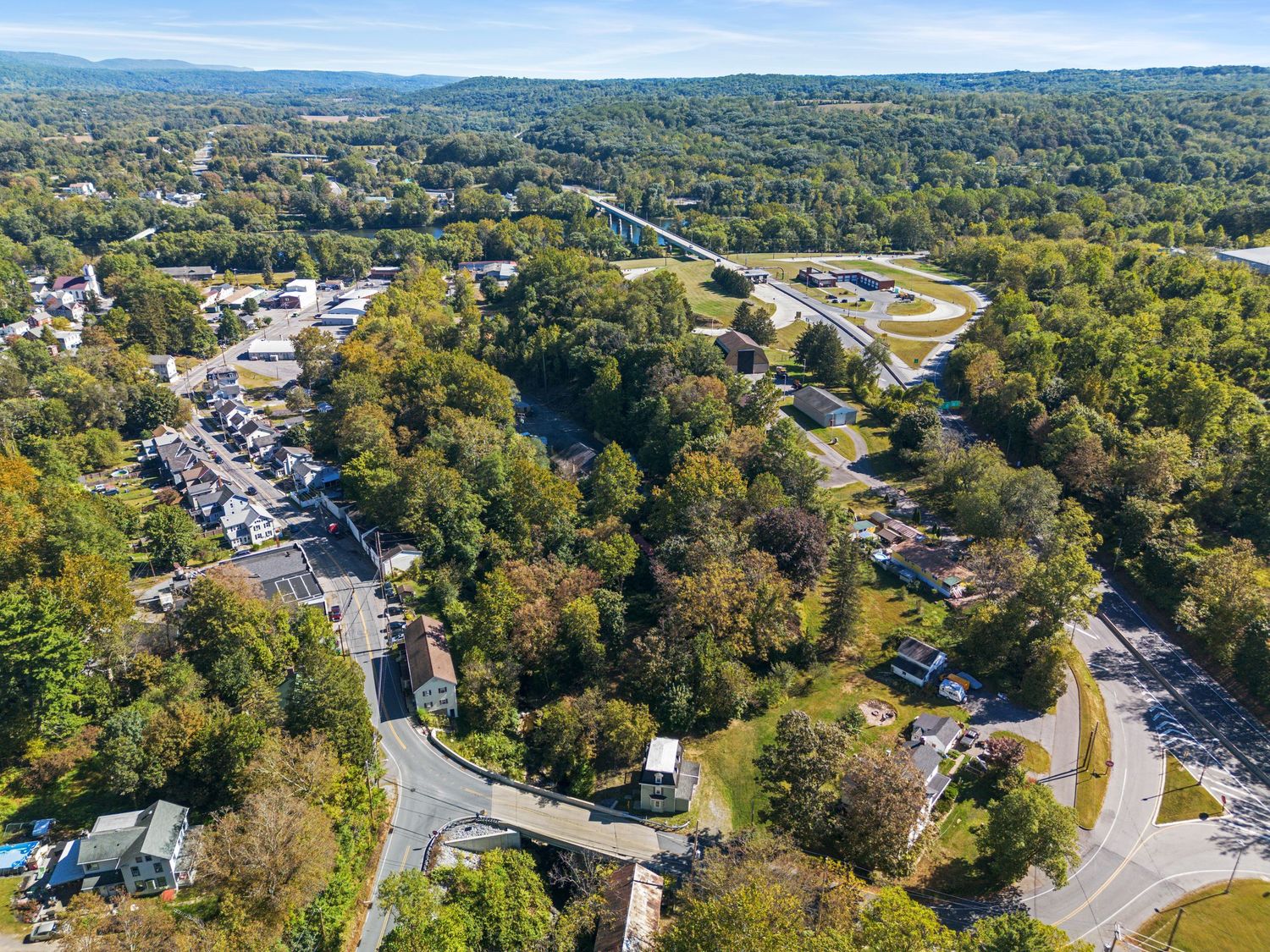 Scenic aerial view of a mountainous landscape with buildings and roads nestled among dense forest.