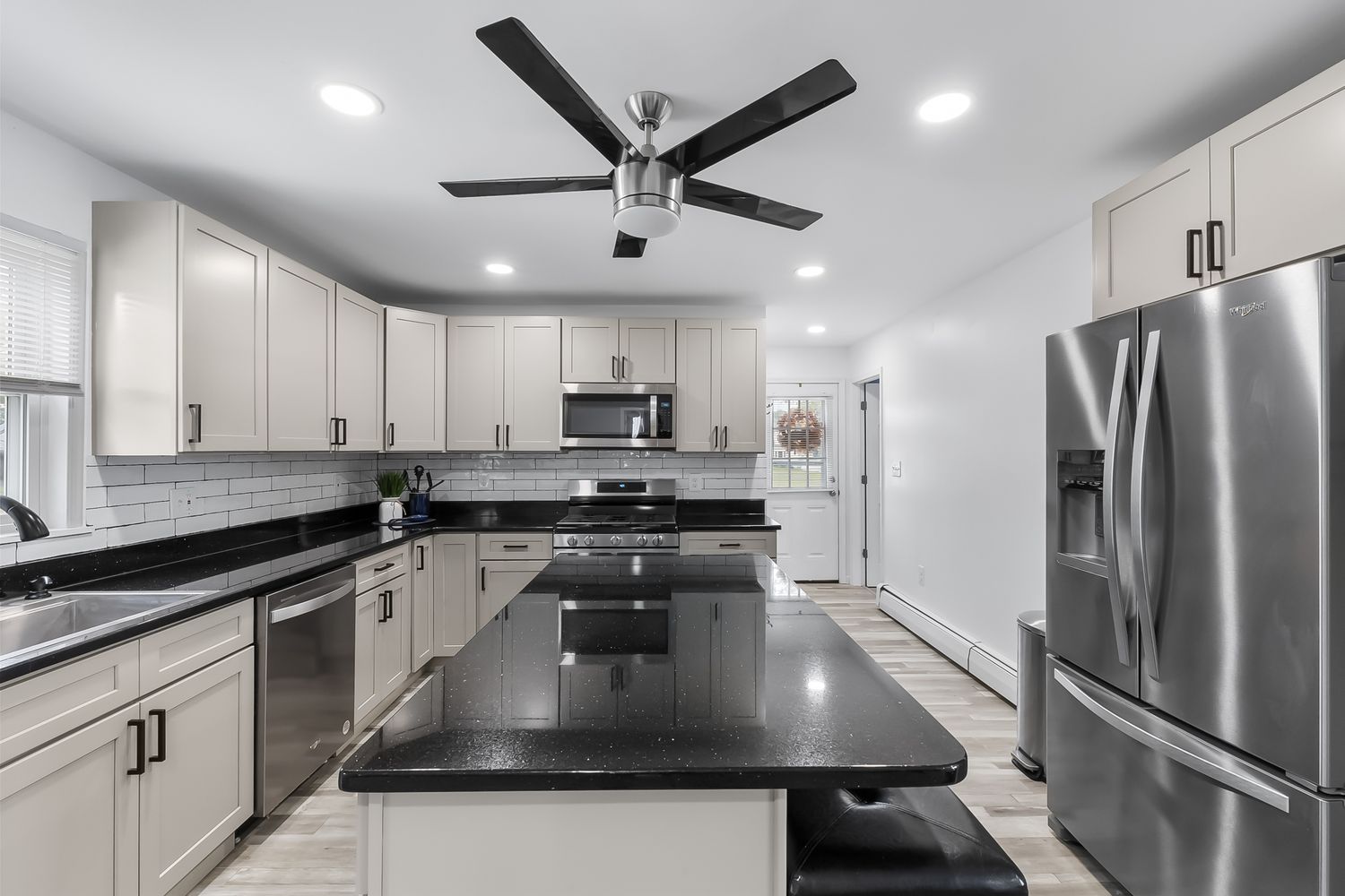 Modern white kitchen with stainless steel appliances and black granite countertops.
