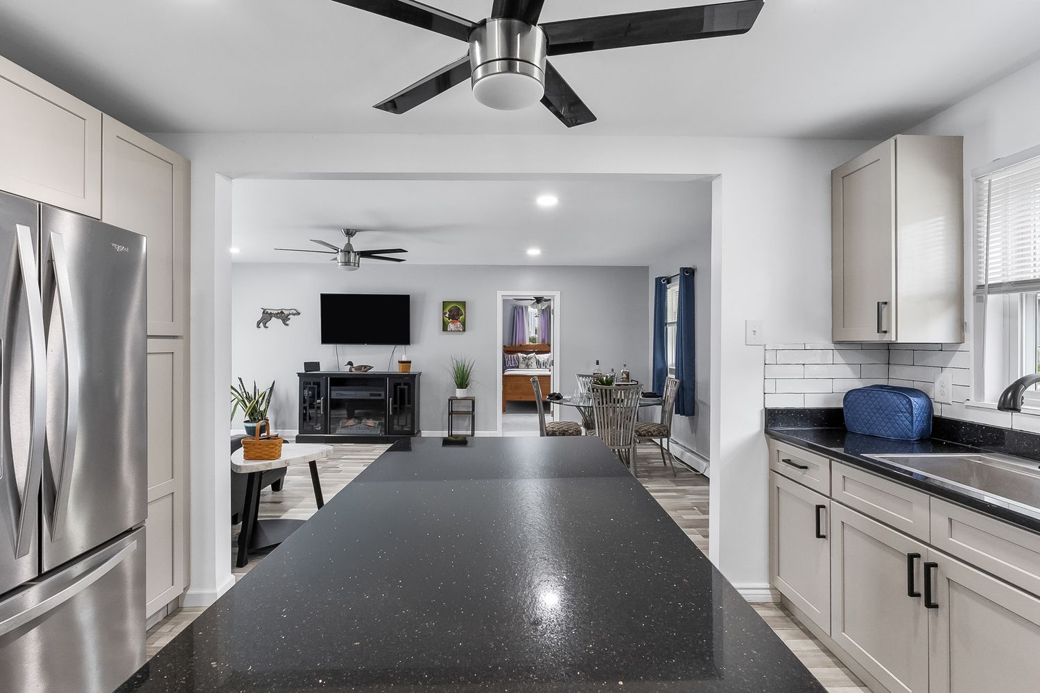Long view of an open concept kitchen with modern appliances and white cabinetry.