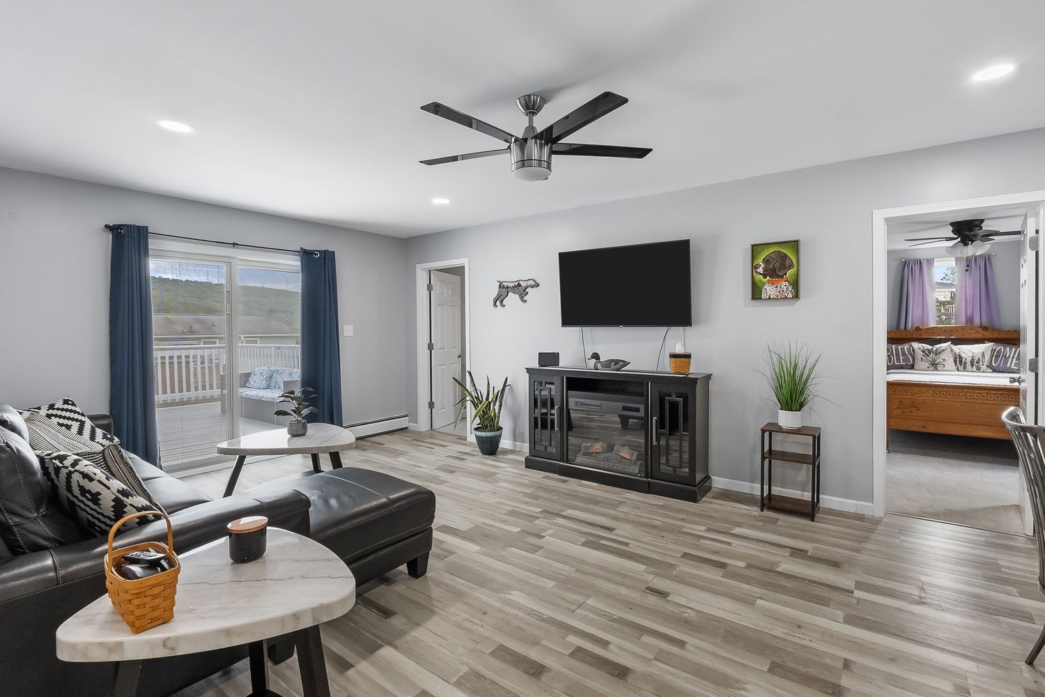 Contemporary living room with wood-look flooring, mounted TV, and modern furniture.