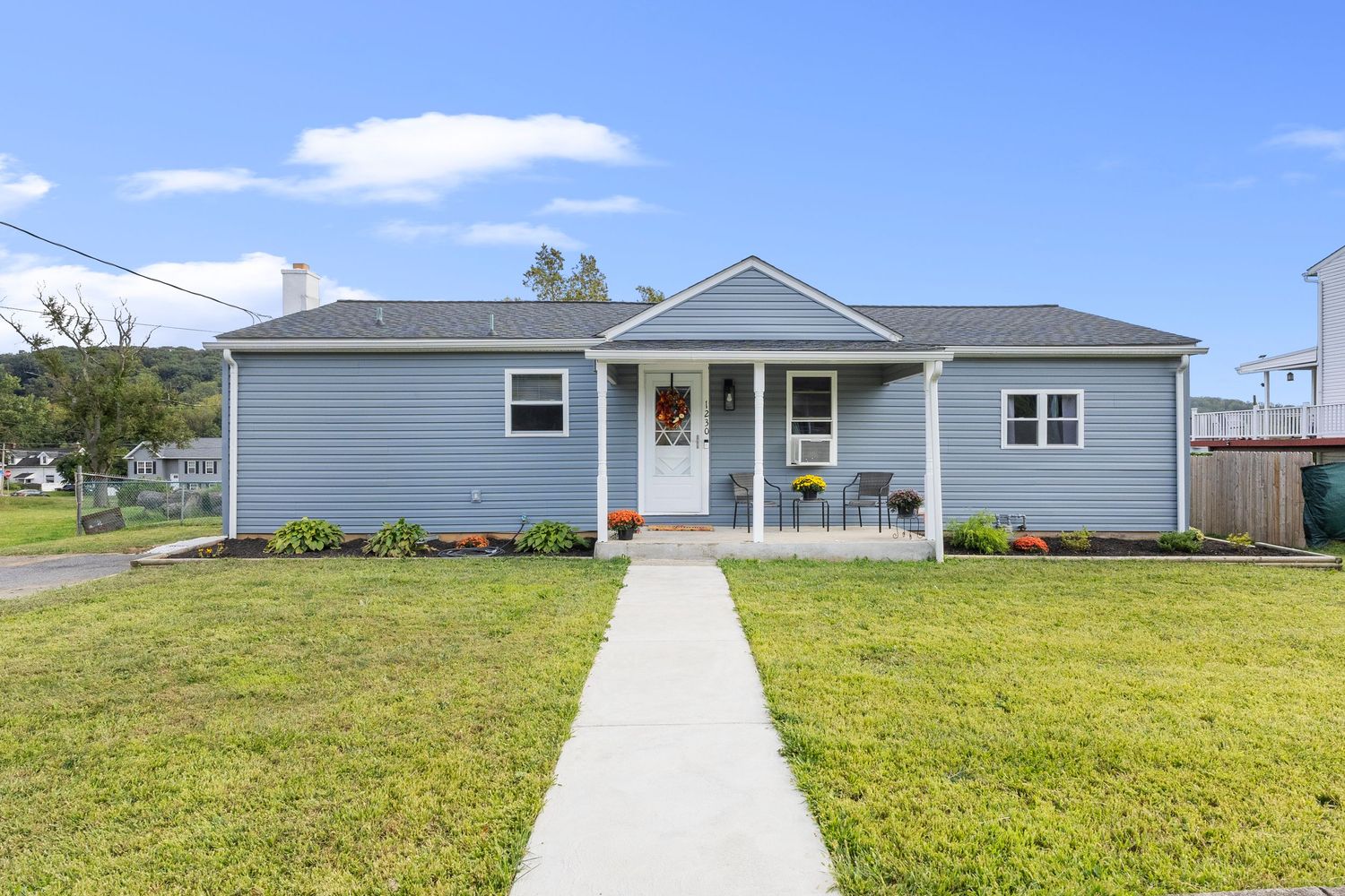 Front exterior view of gray residential home with manicured lawn and concrete path.