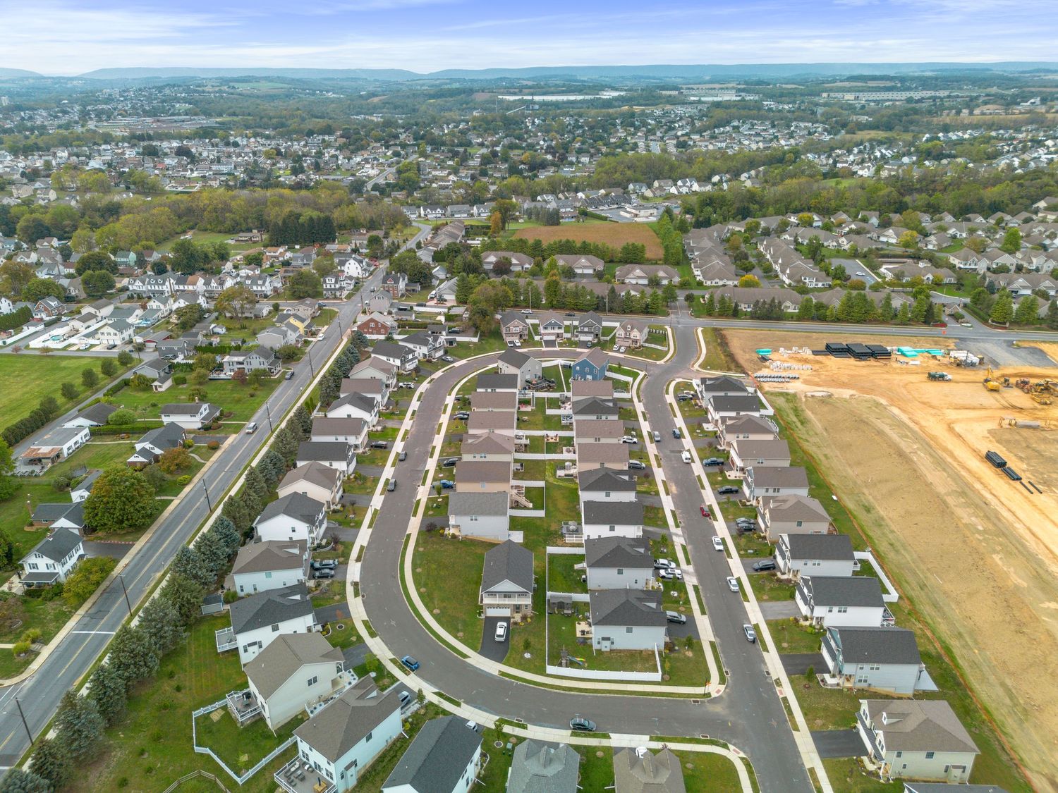 Wide aerial panorama of planned residential development with rows of single-family homes.