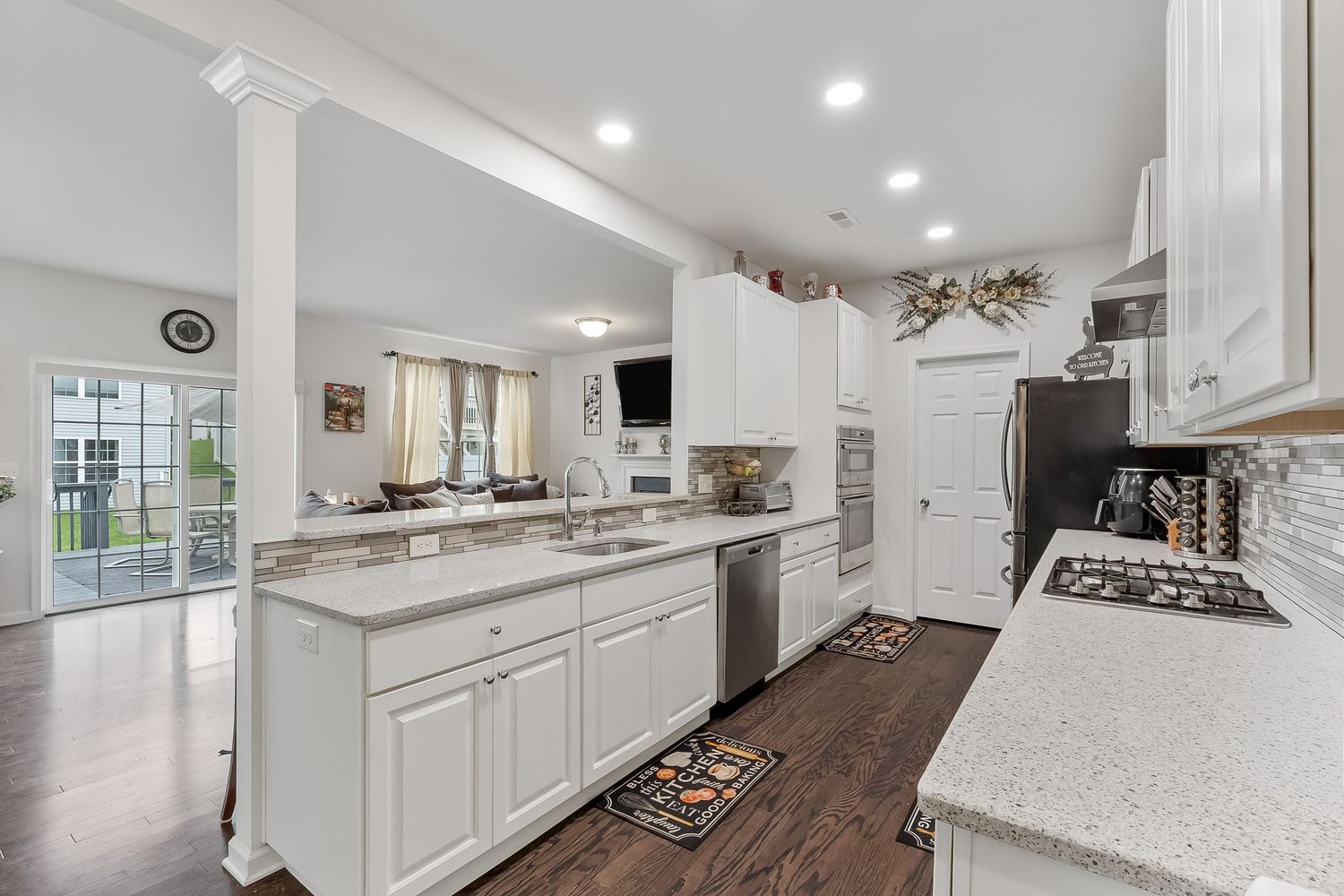 Contemporary white kitchen with granite countertops, stainless appliances and recessed lighting.