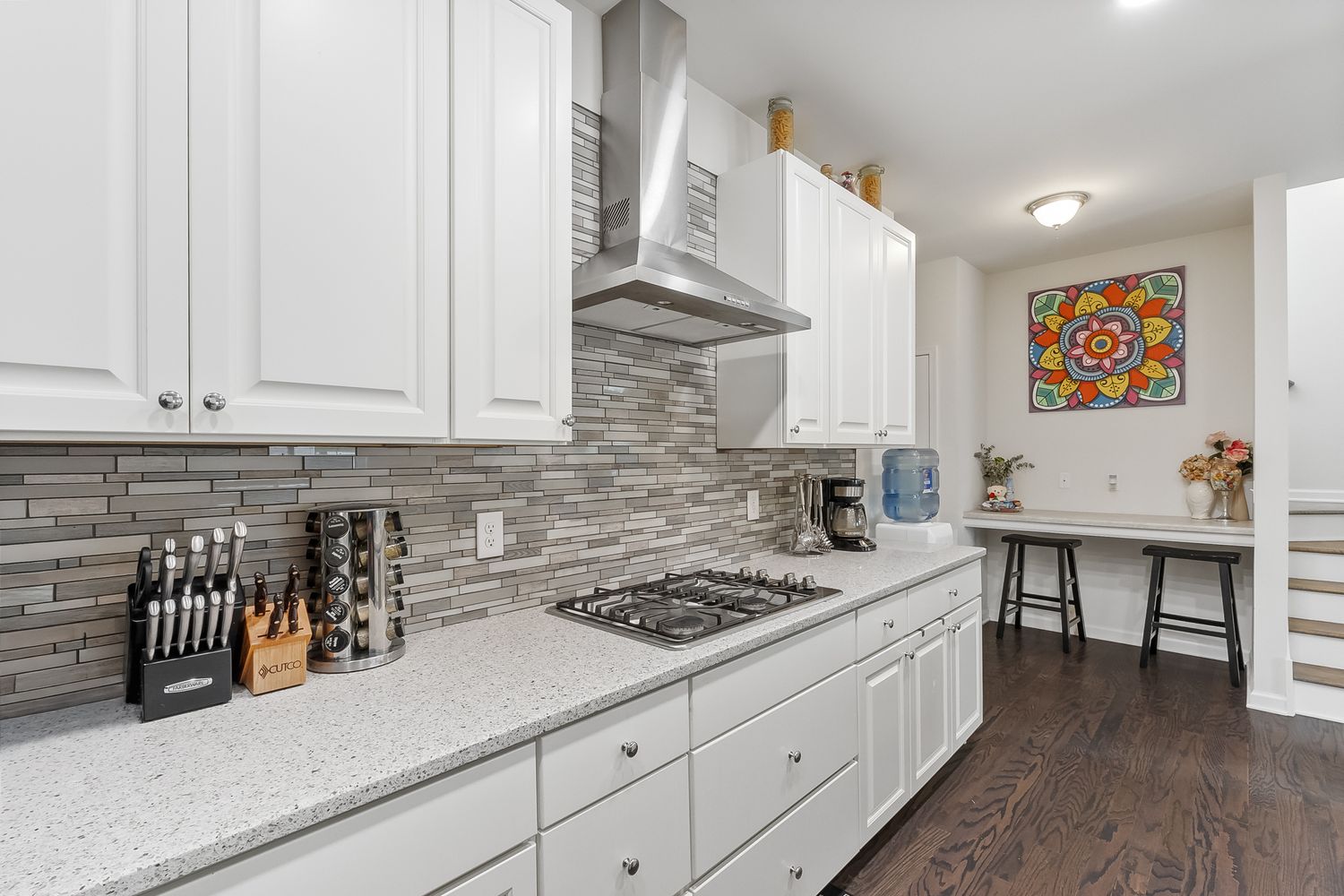 Spacious white kitchen featuring long granite countertops and modern cabinetry.