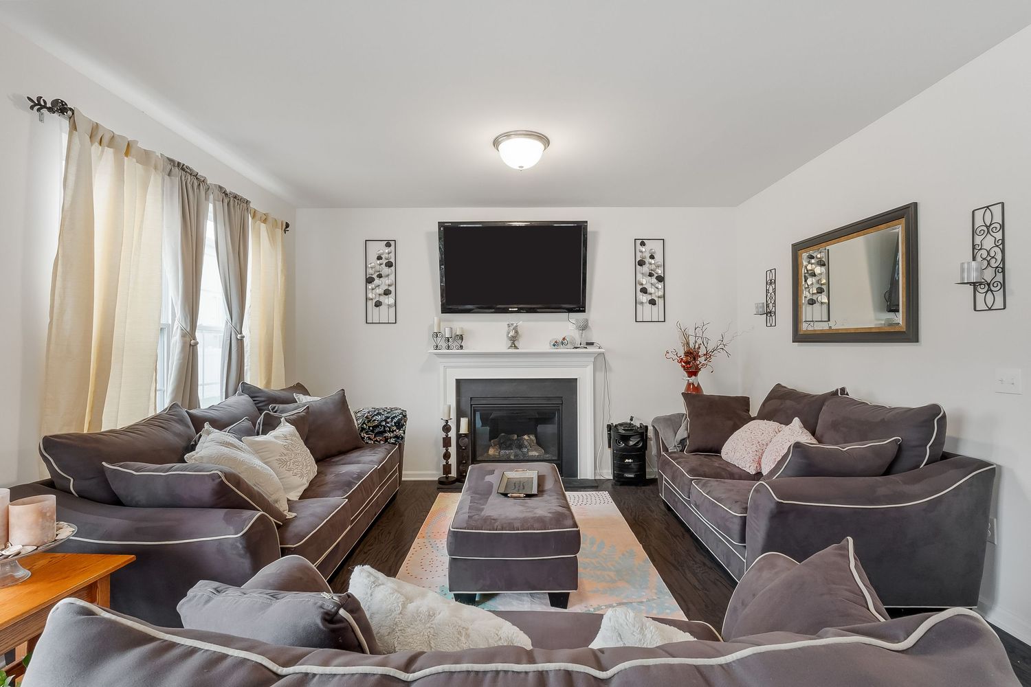Living room interior with plush grey sofas and wall-mounted television.