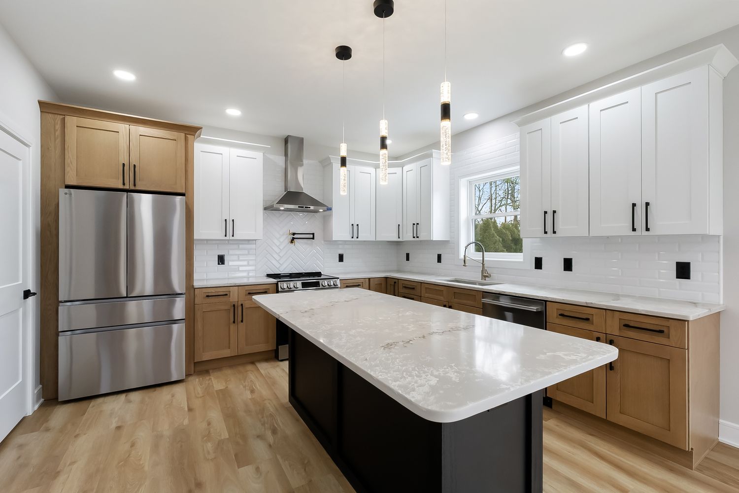 Modern white kitchen with quartz countertops, stainless steel appliances, and light wood flooring.