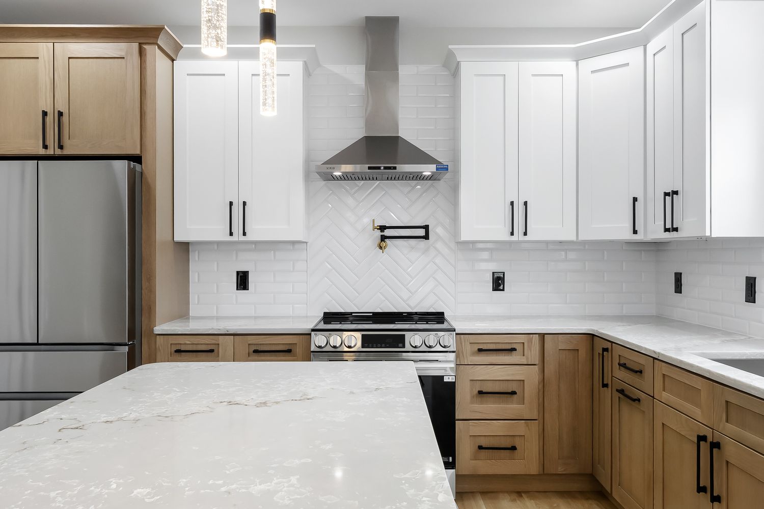 Modern kitchen with white upper cabinets, wood lower cabinets, and stainless steel appliances features a sleek design.