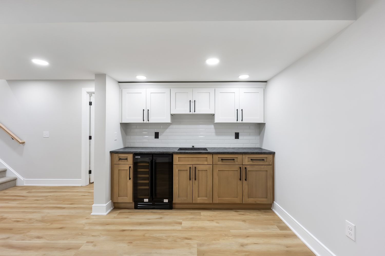 Contemporary open concept kitchen with white cabinets and hardwood flooring in a minimalist design.