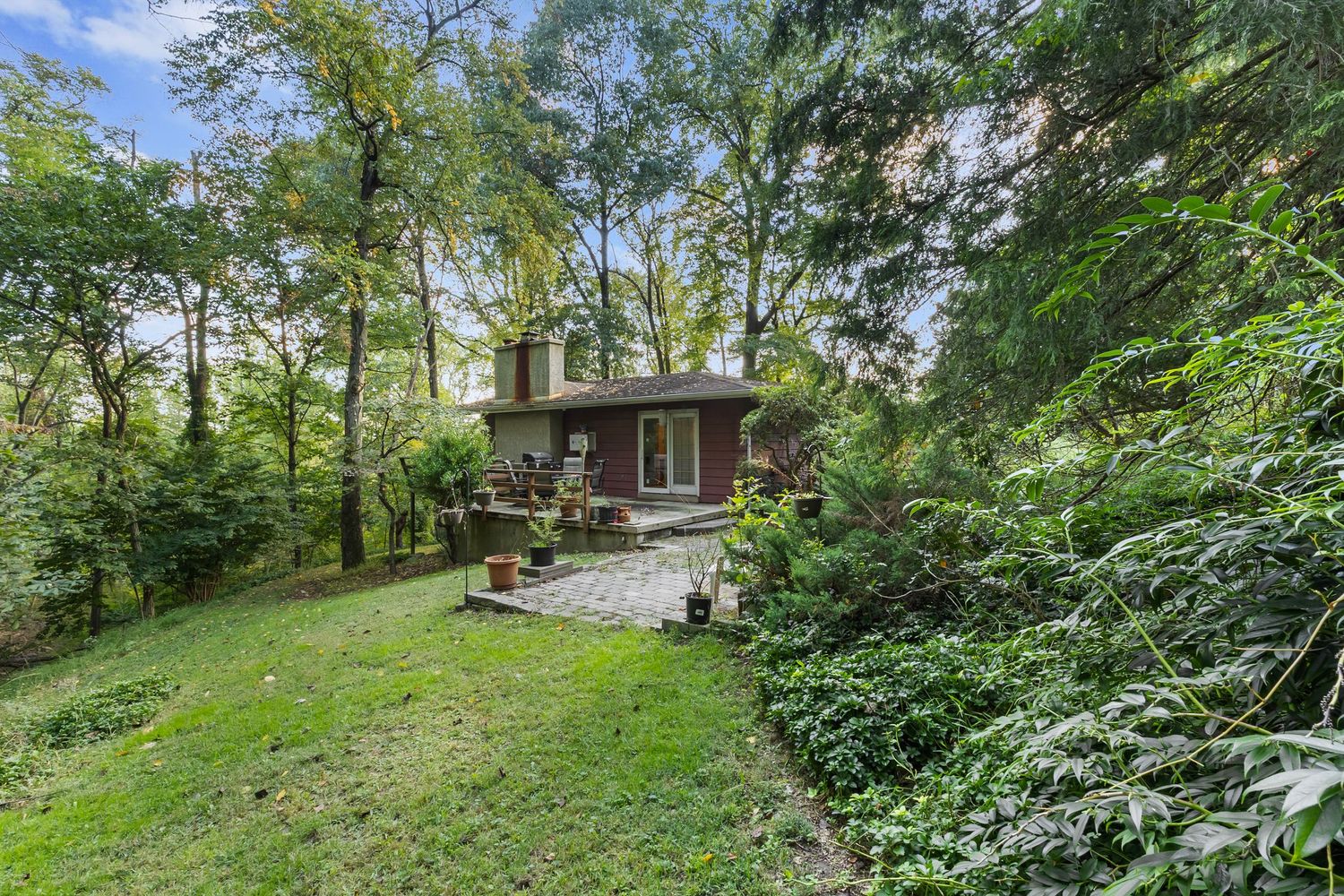 Wooded property with green landscaping and natural stone features surrounded by mature trees.