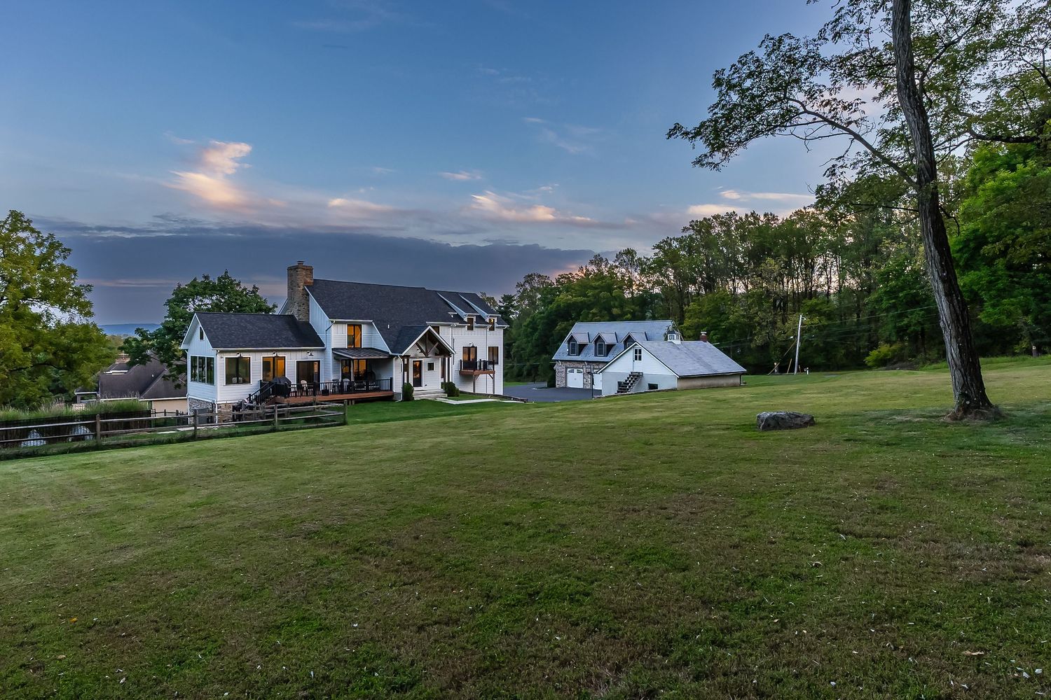 Rural property with multiple white houses spread across a hilltop landscape at dusk.