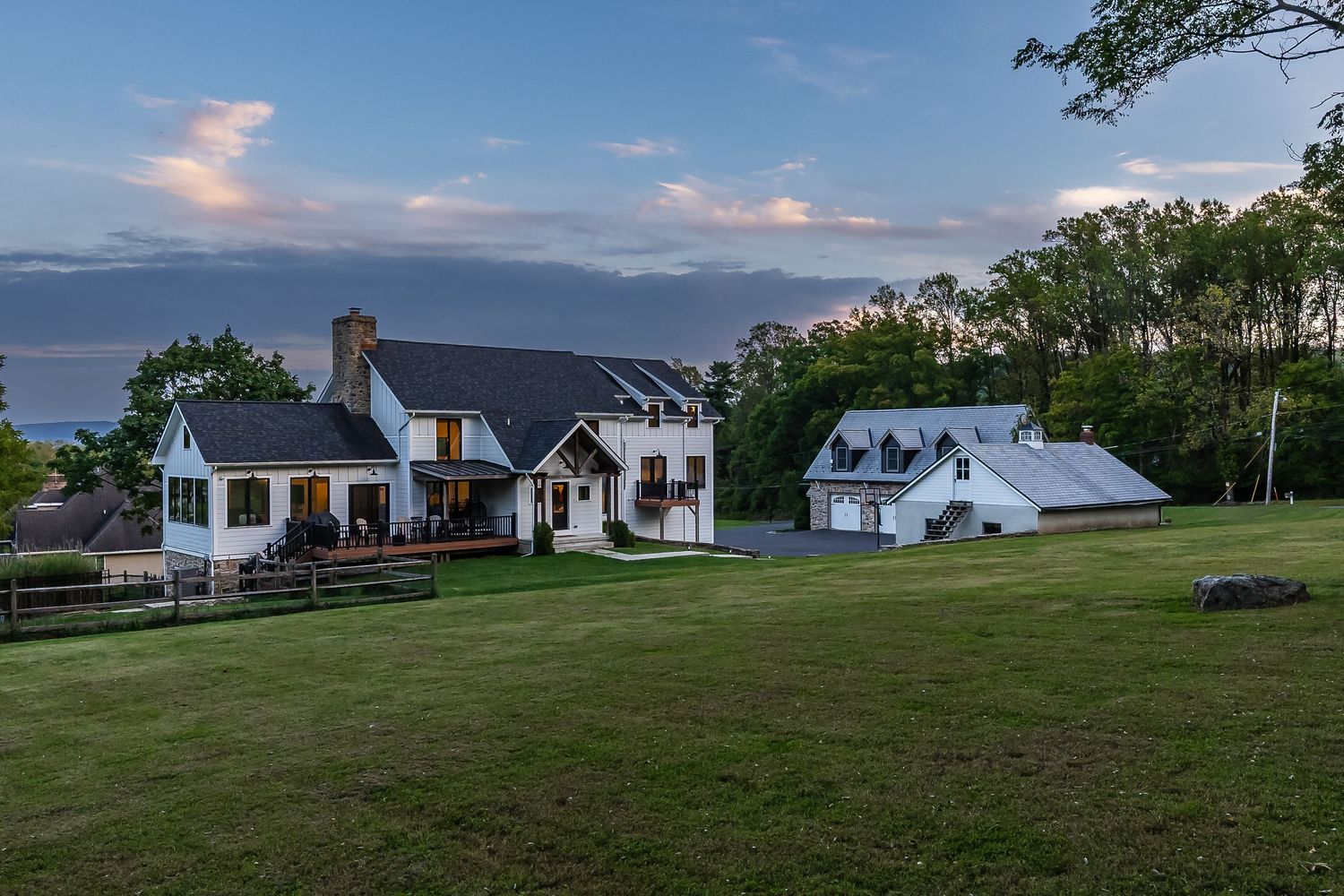 Panoramic view of white country homes situated on rolling hills under evening sky.