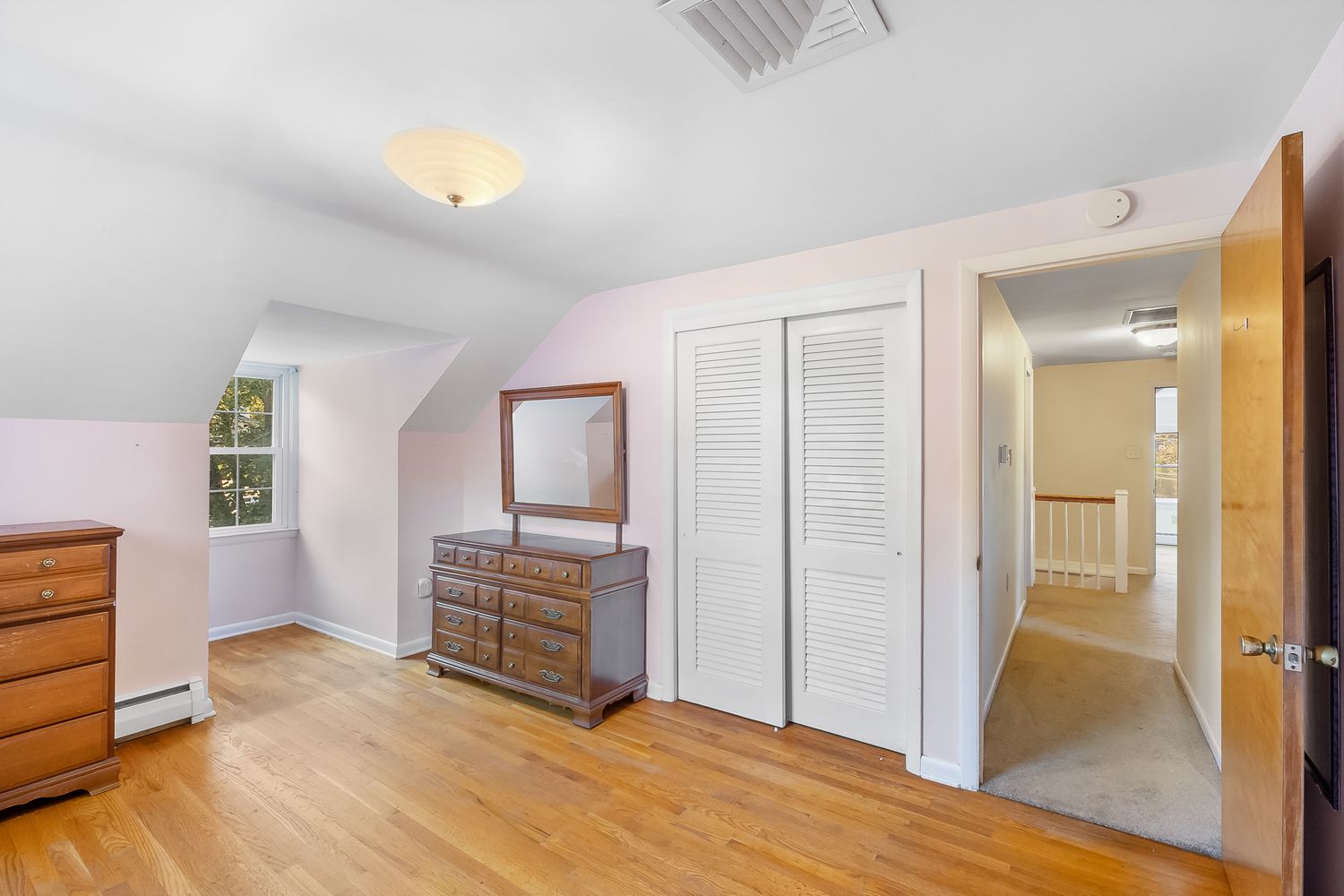 Spacious white attic room with wooden floors and built-in storage spaces.