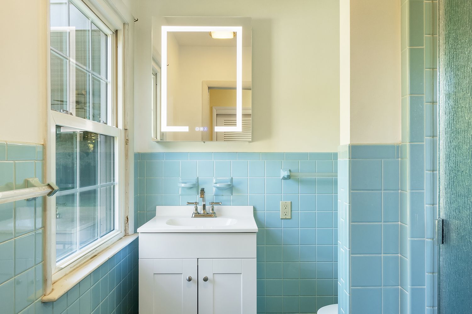 Modern bathroom interior with blue tile walls and white fixtures.