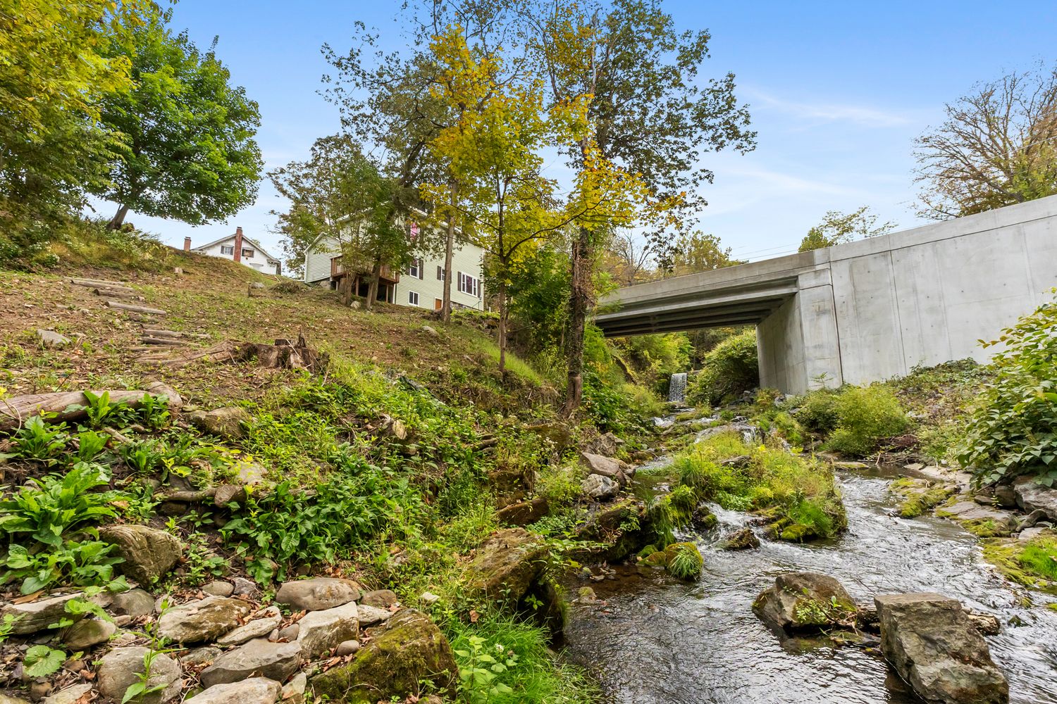 Natural stream flowing through rocky terrain with lush green vegetation.