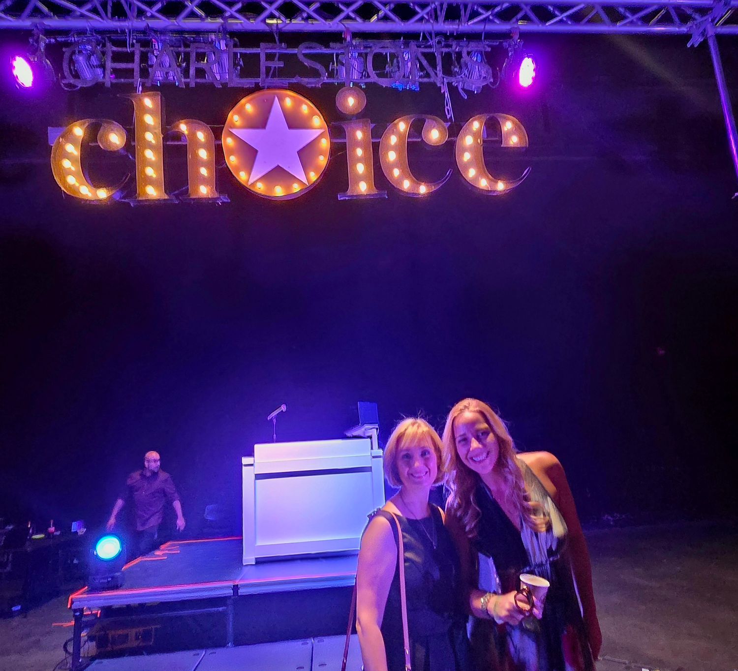 A concert stage lit with purple and blue lighting features performers during a live music performance.