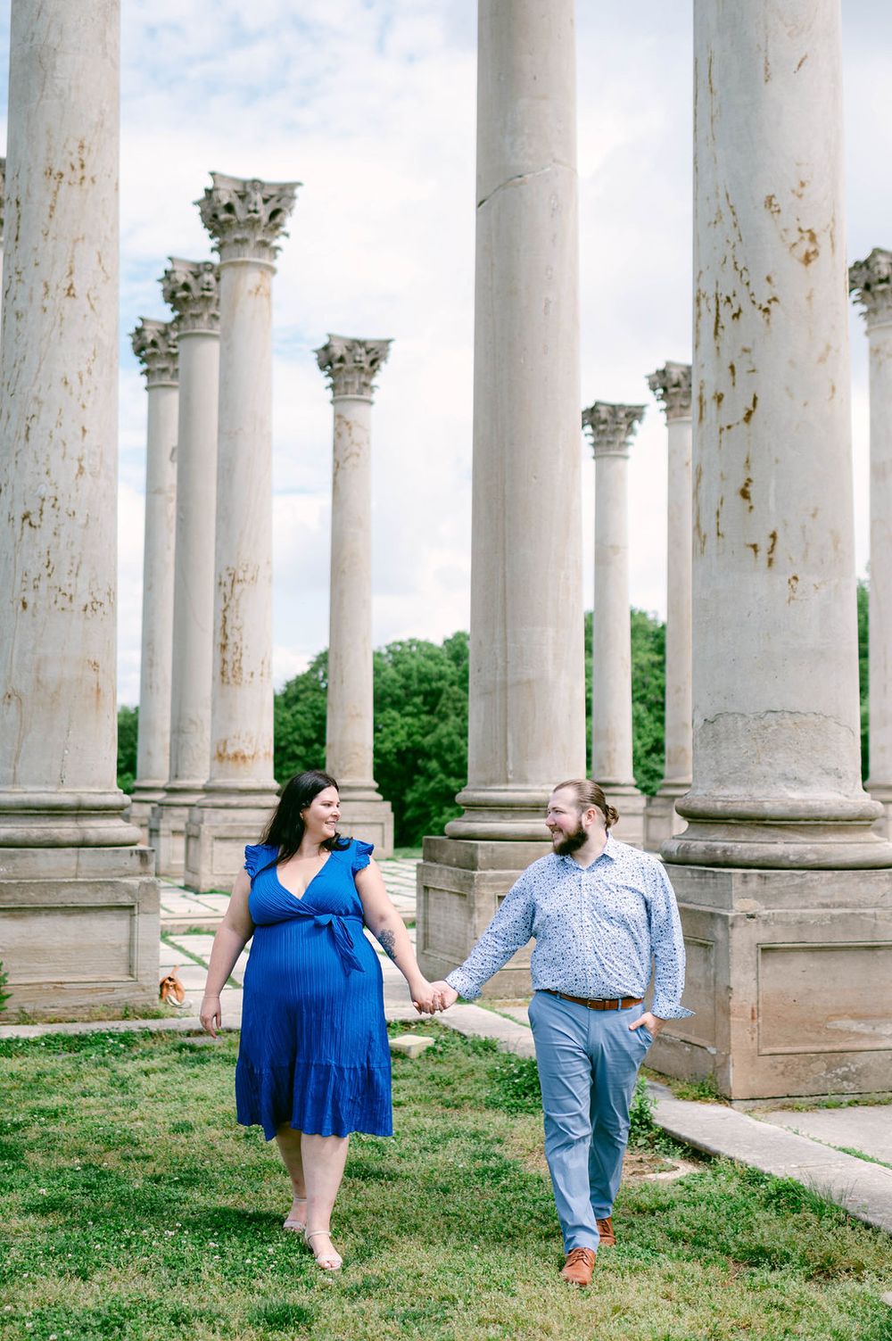 A couple sits among elegant white stone columns at the National Arboretum in Washington DC during an engagement photo session.