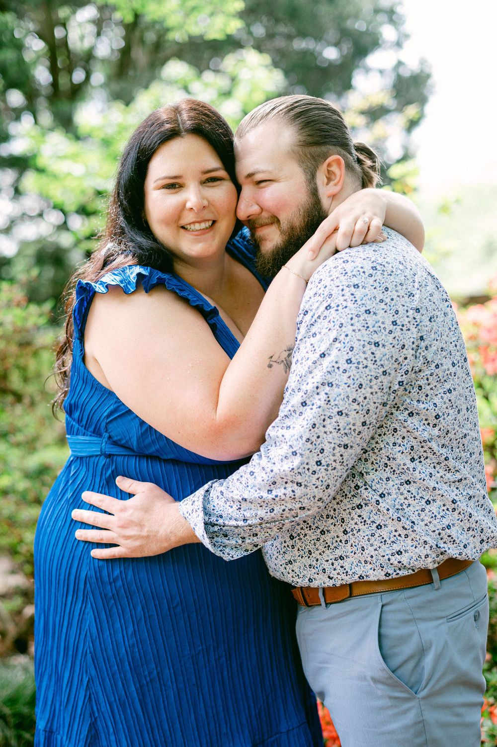 A couple shares tender embraces and laughter in a series of romantic outdoor photos wearing blue and floral patterns.